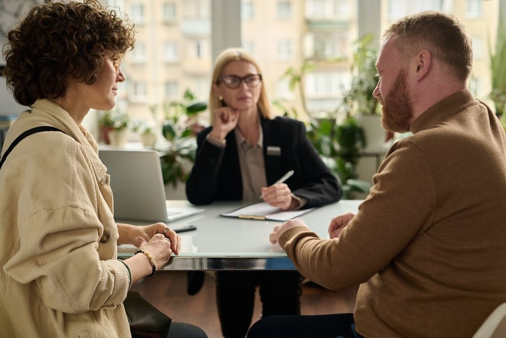 A man and a woman are sitting at a table talking to a woman.