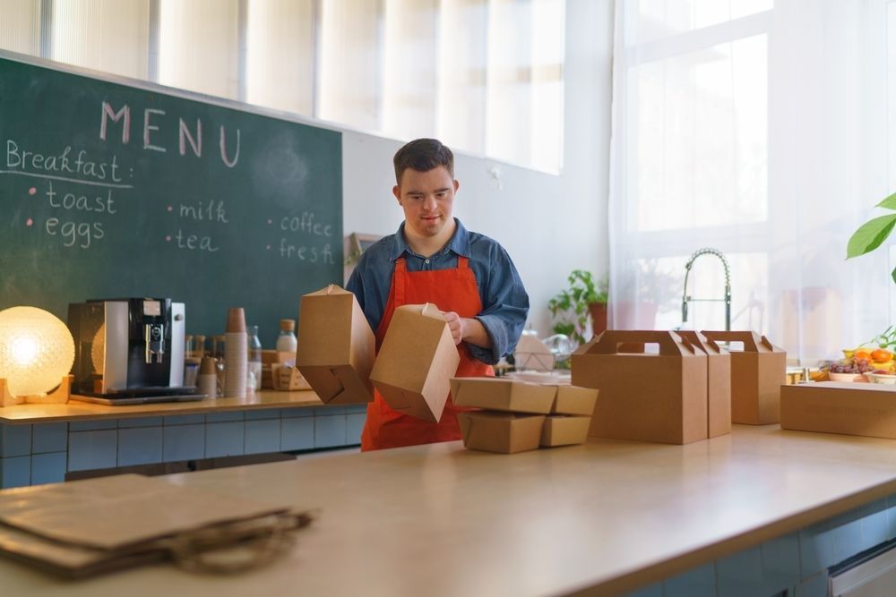Man in a Café Wearing an Orange Apron — Adaptive Care Pty Ltd In Preston, VIC