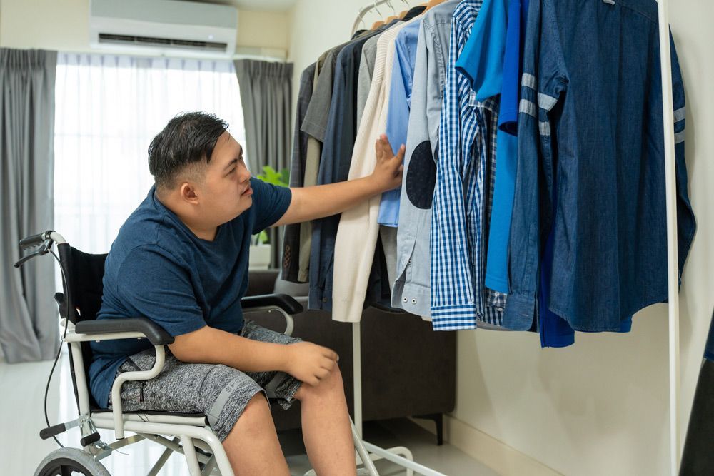 A Person in a Wheelchair Looking at Clothes From a Rack — Adaptive Care Pty Ltd In Tarneit, VIC