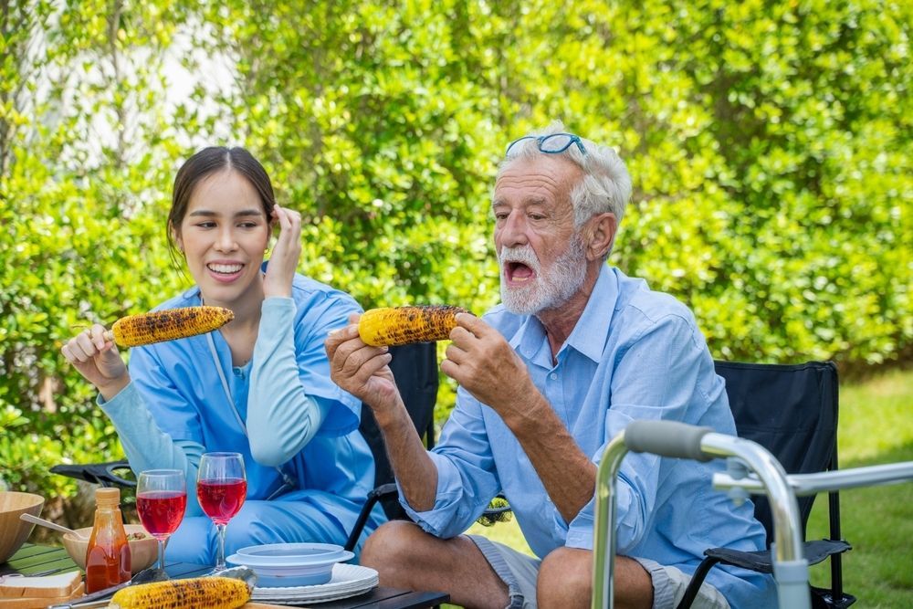 Man and a Woman Enjoy Grilled Corn Outdoors — Adaptive Care Pty Ltd In Geelong, VIC