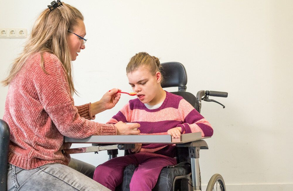 A Woman in a Red Sweater Feeds a Child — Adaptive Care Pty Ltd In Tarneit, VIC