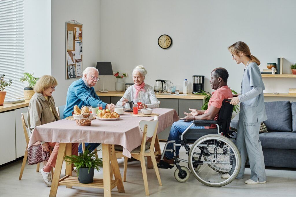 Elderly Individuals and a Caregiver Gather Around a Table — Adaptive Care Pty Ltd In Epping, VIC