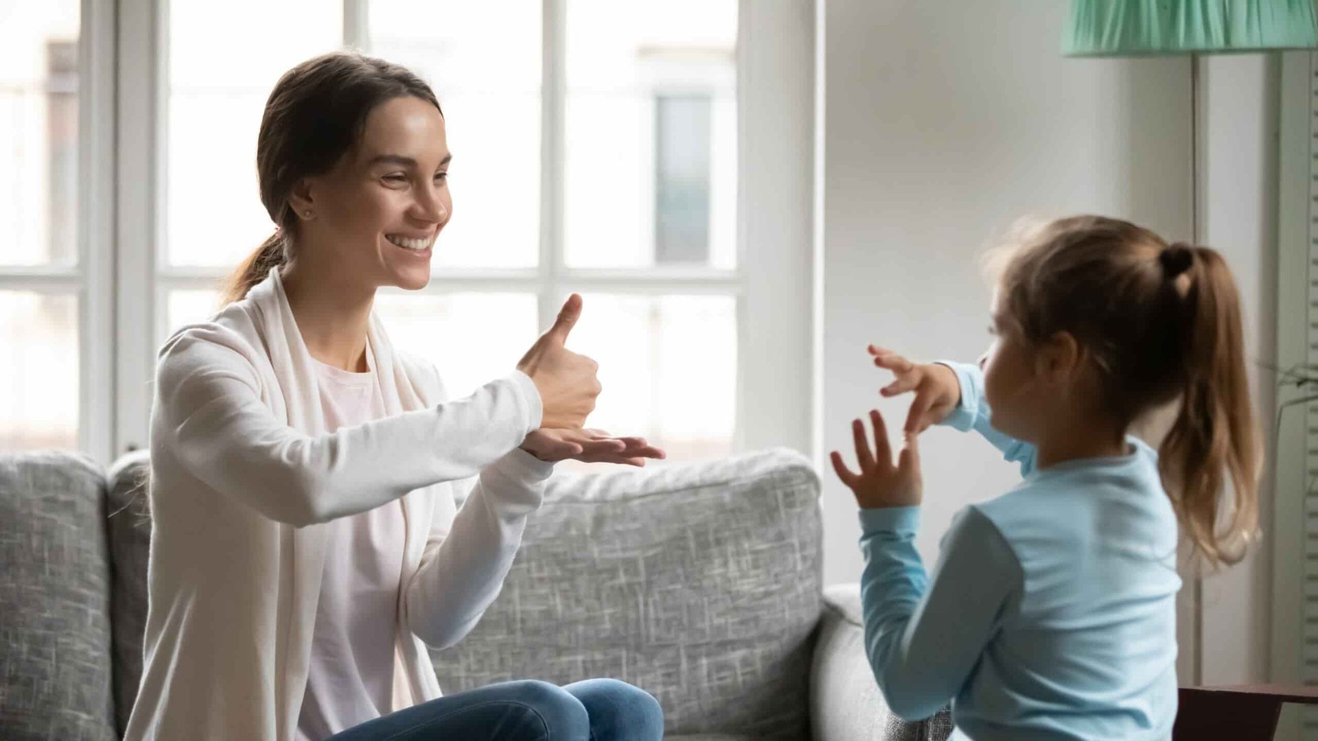 A Woman And A Little Girl Are Sitting On A Couch Playing With Their Hands — Adaptive Care Pty Ltd In Sunshine, VIC