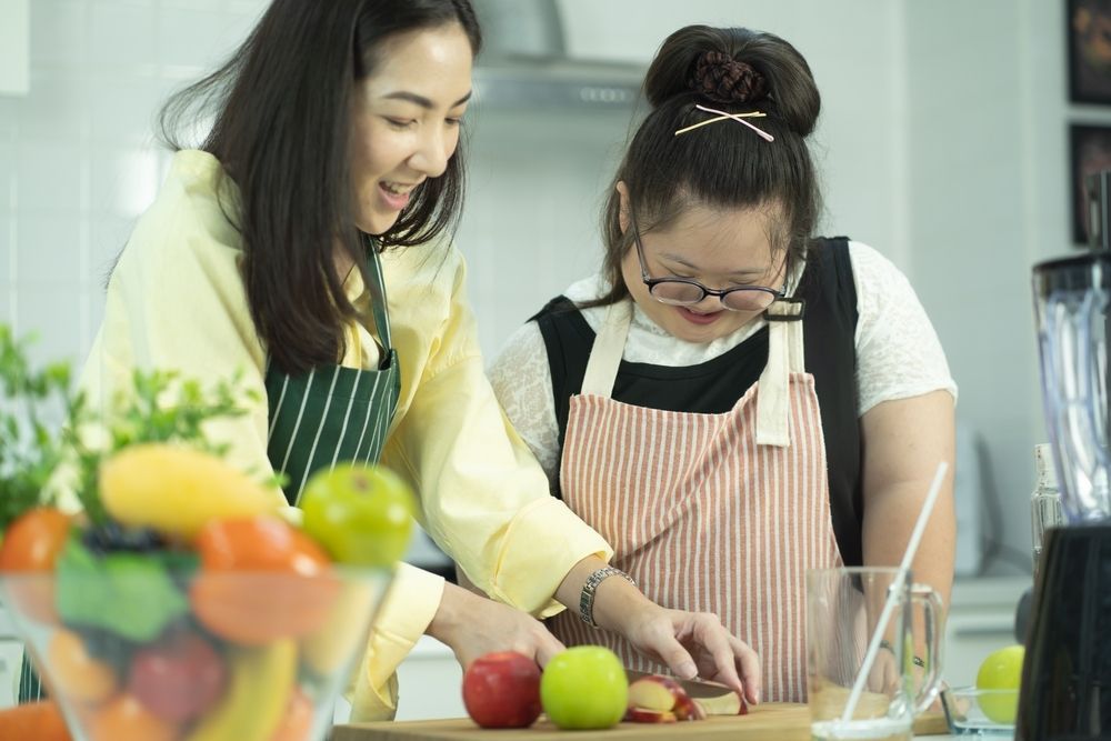 Two Women Joyfully Slice Fruit in a Kitchen — Adaptive Care Pty Ltd In Melton, VIC
 