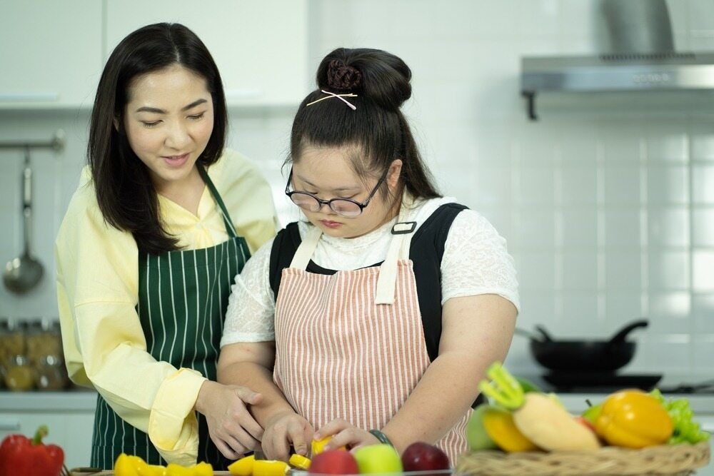 Woman and Young Girl in Aprons Cutting Vegetables — Adaptive Care Pty Ltd In Melton, VIC