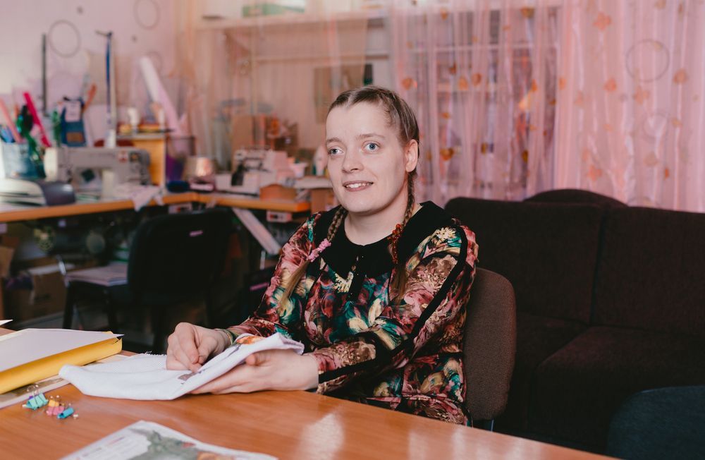 A Woman Holds Fabric at a Wooden Table — Adaptive Care Pty Ltd In Cranbourne, VIC