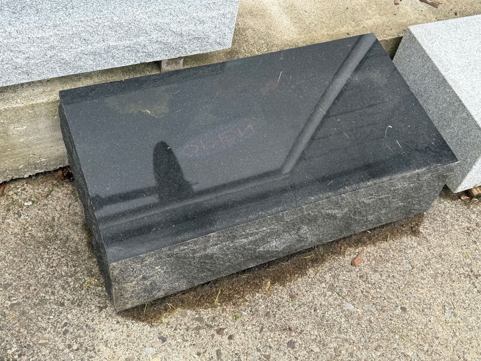 A black granite slab is sitting on top of a concrete surface.