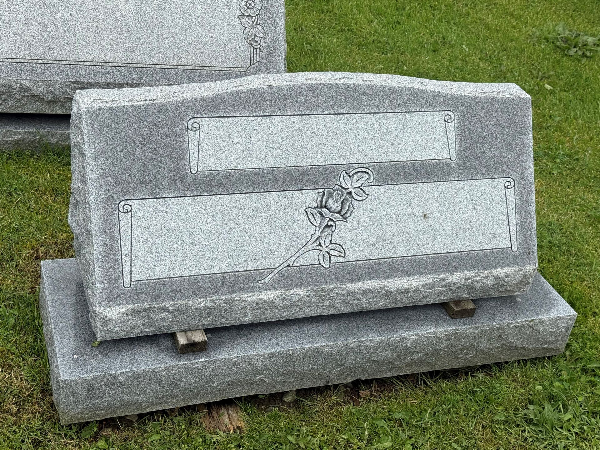 A gravestone is sitting in the grass in a cemetery.