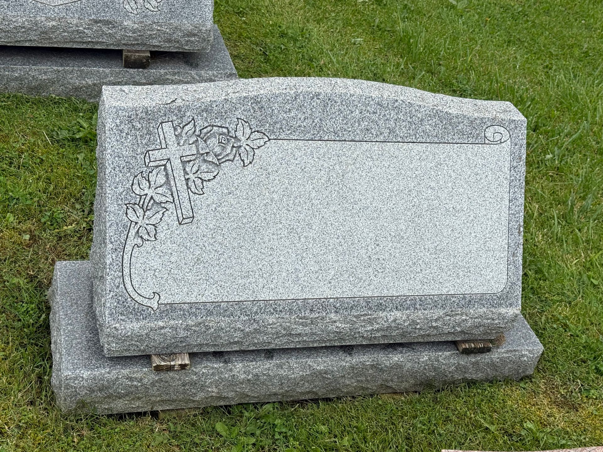 A gravestone is sitting in the grass in a cemetery.