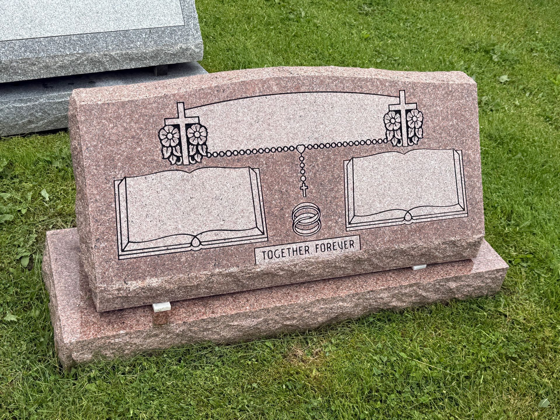 A gravestone is sitting on top of a lush green field.