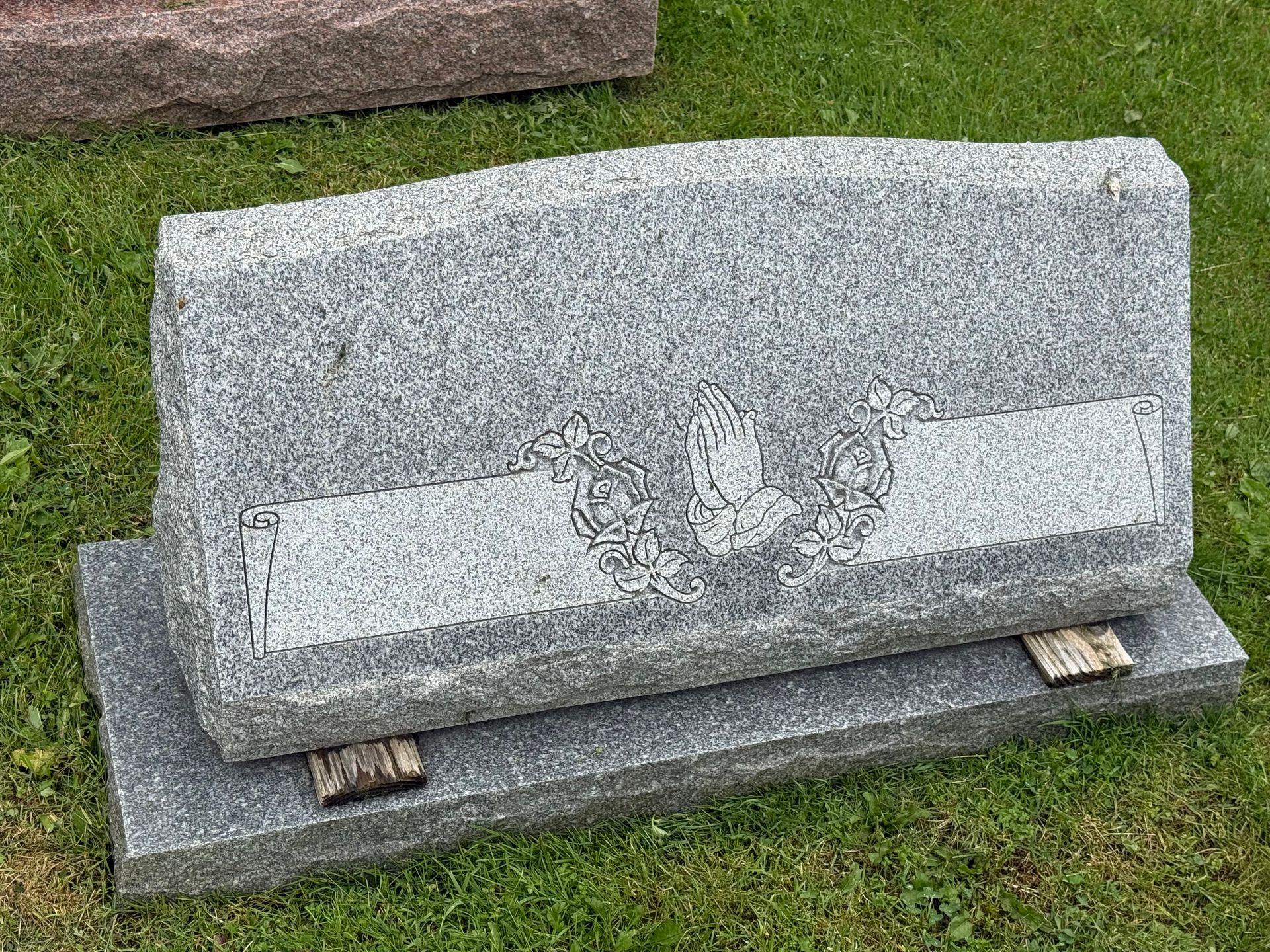 A gravestone is sitting on top of a grass covered field.
