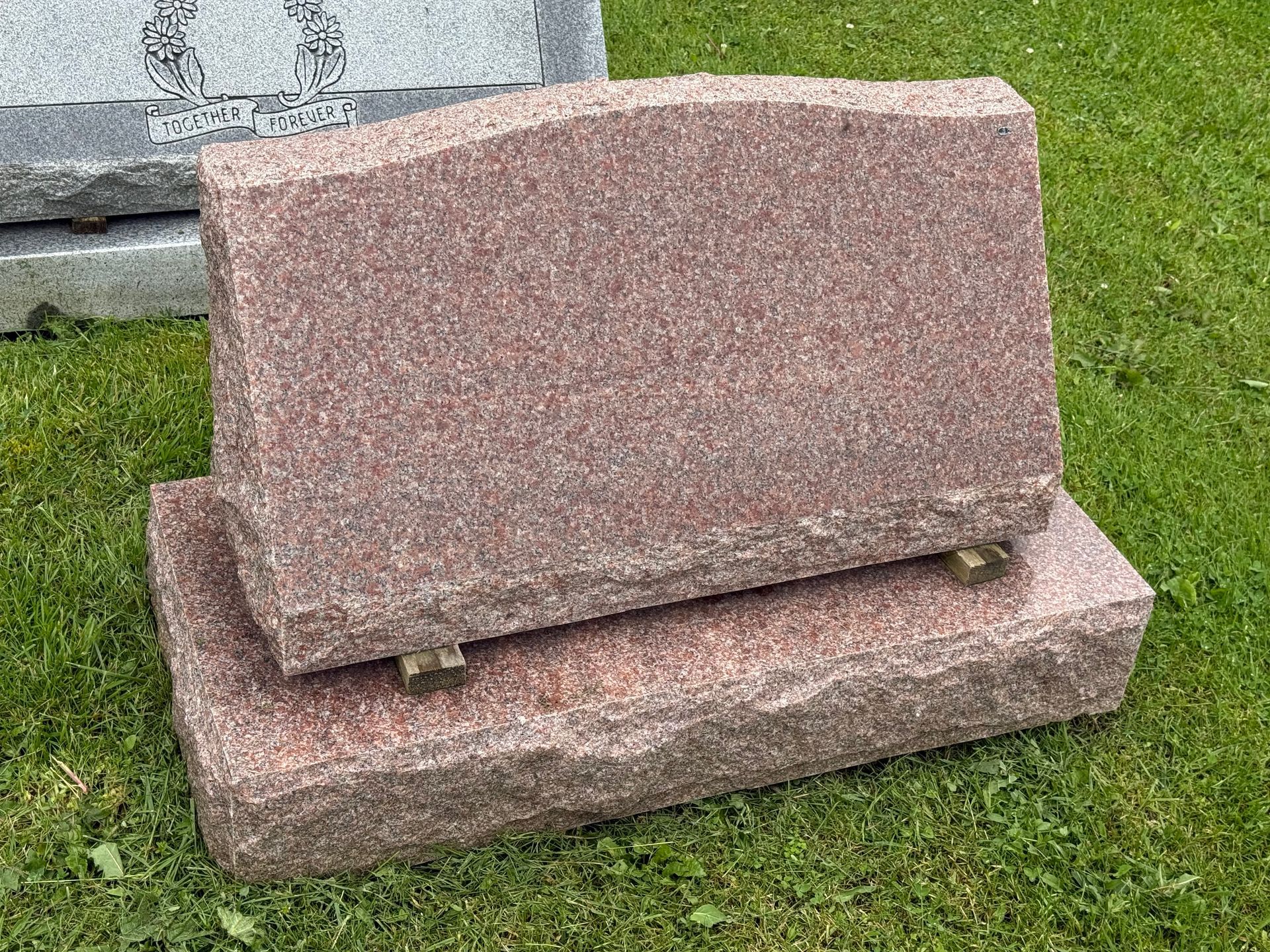 A gravestone is sitting on top of another gravestone in a cemetery.