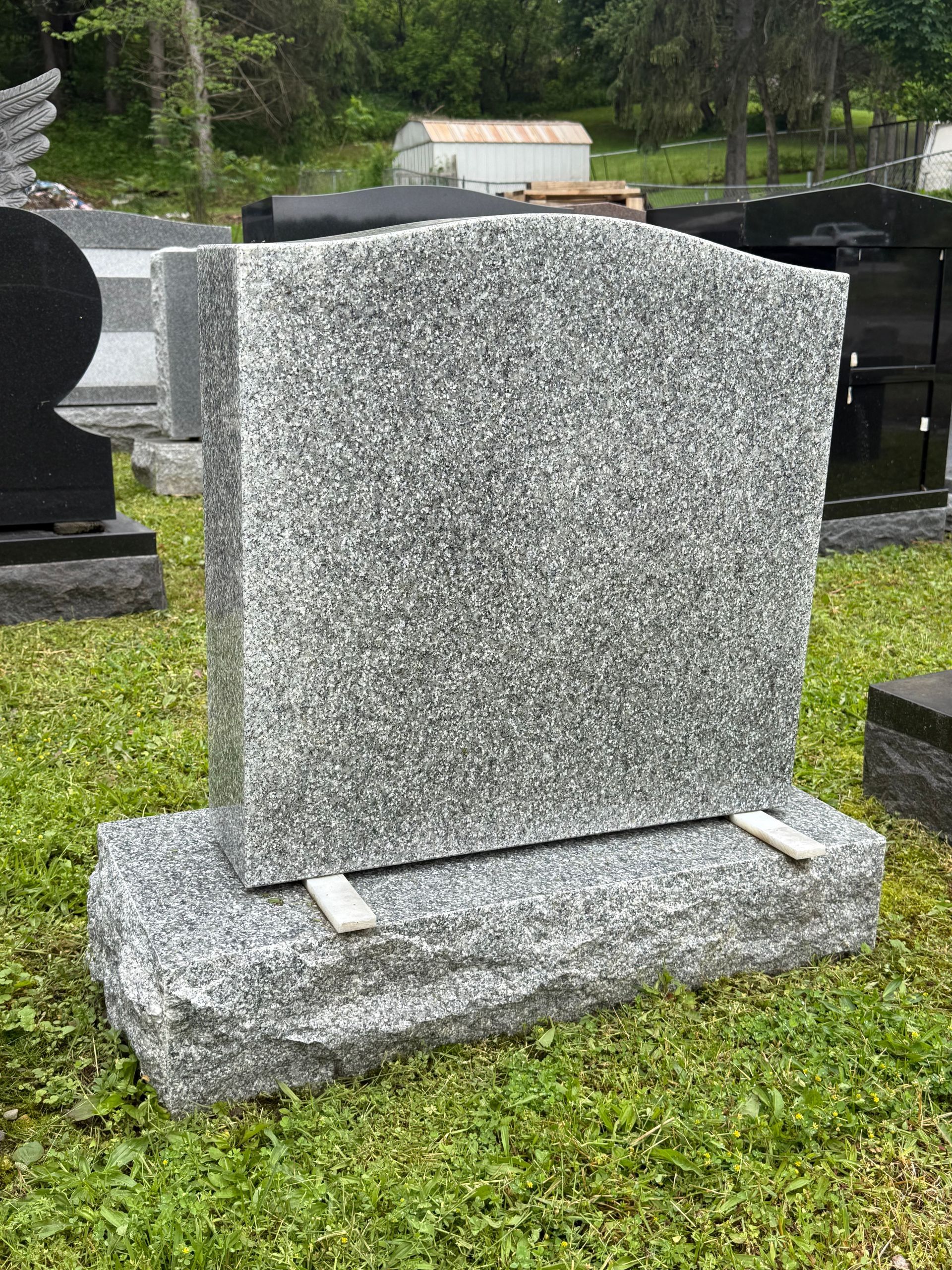 A gravestone is sitting in the grass in a cemetery.