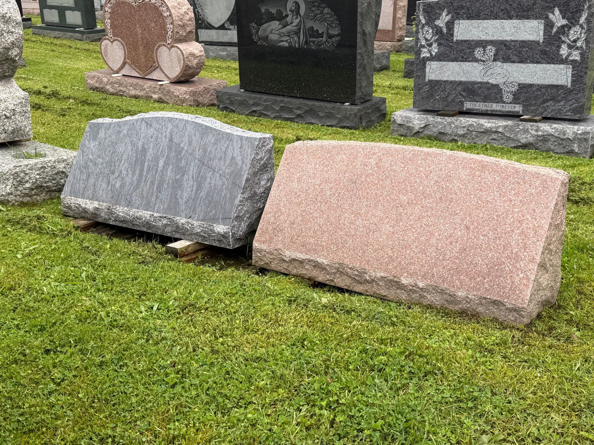A group of gravestones are sitting on top of a lush green field.