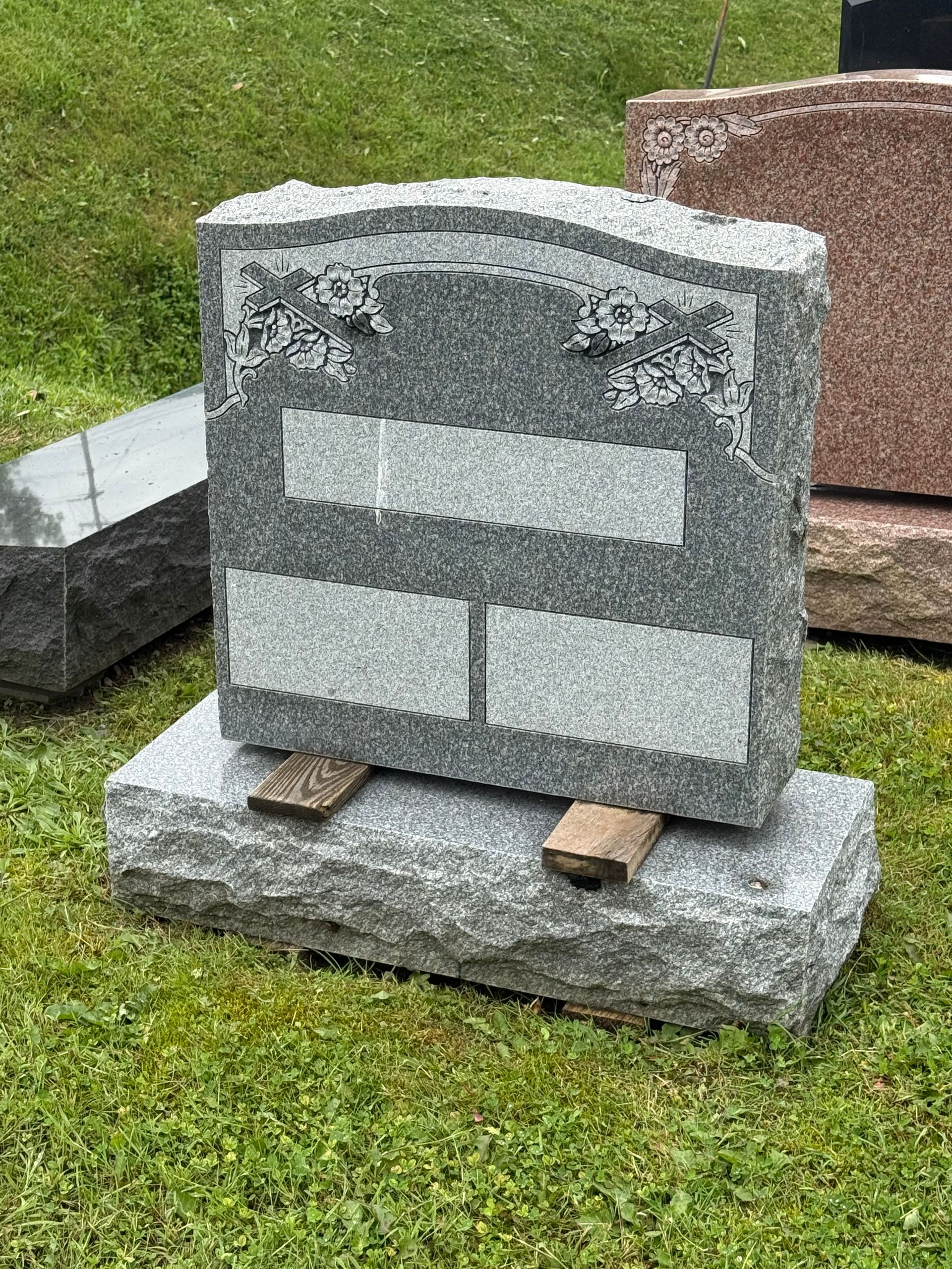 A gravestone is sitting on top of a wooden base in a cemetery.