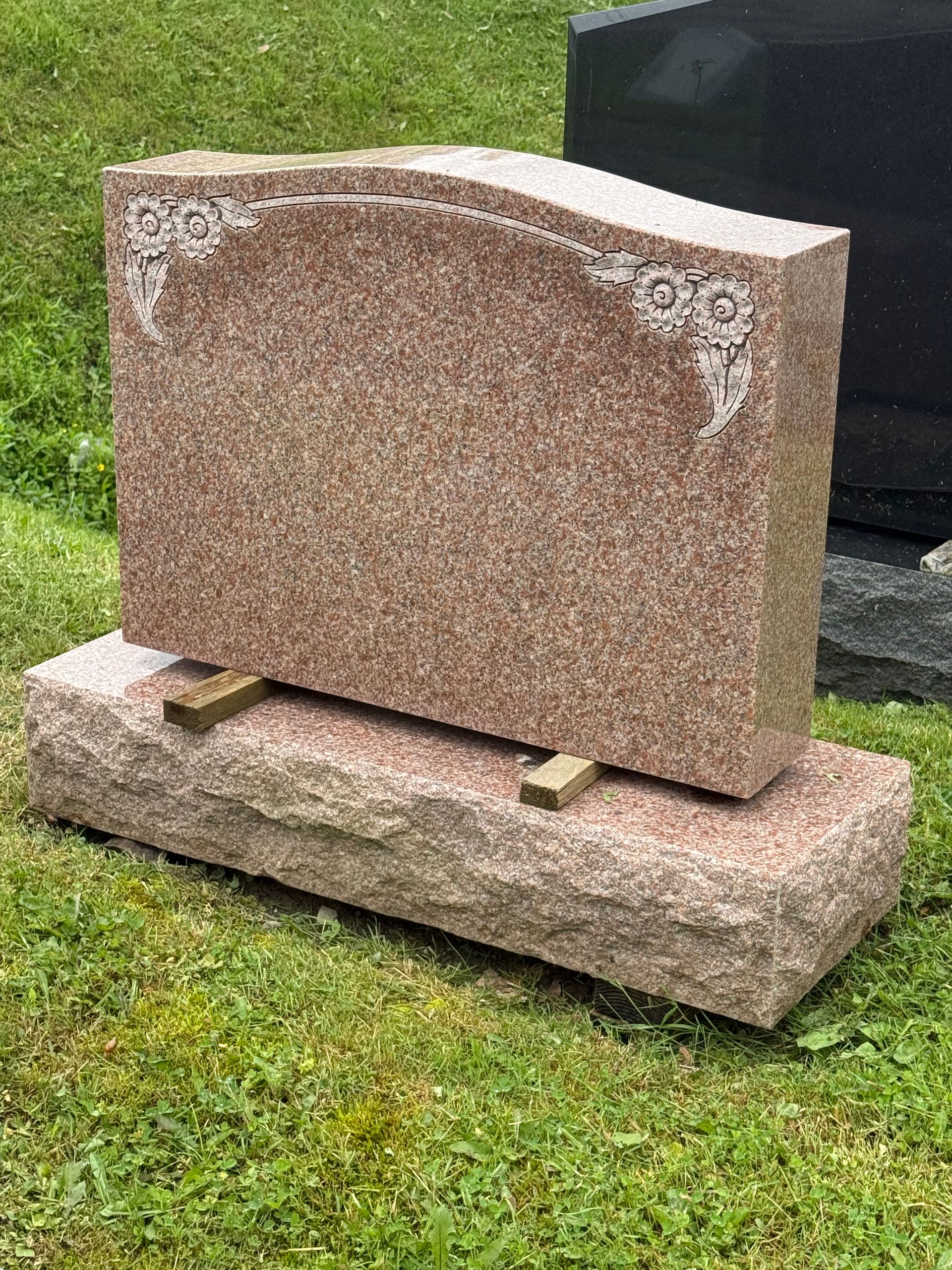 A gravestone is sitting in the grass in a cemetery.