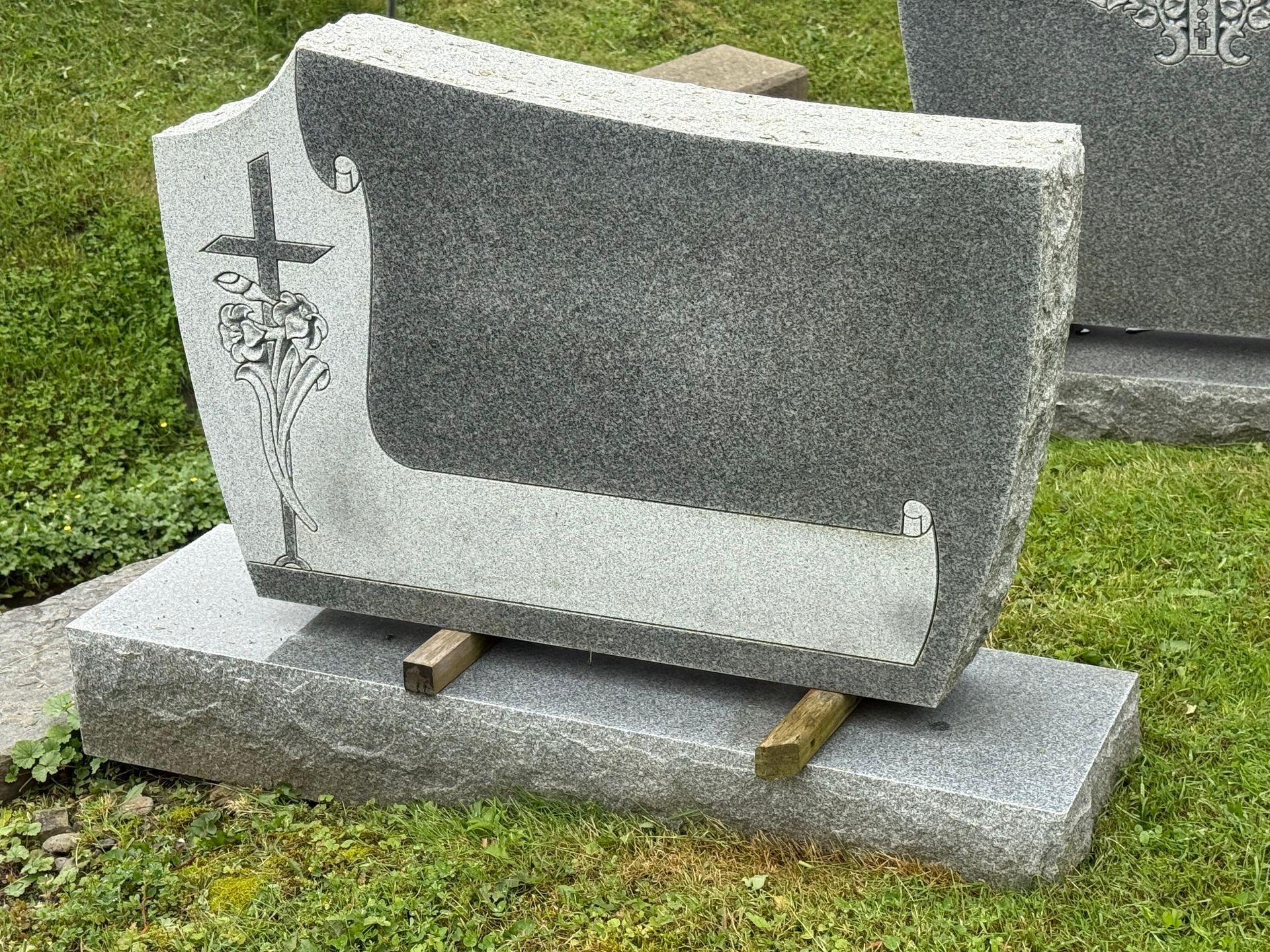 A gravestone with a cross on it is sitting on top of a grave in a cemetery.