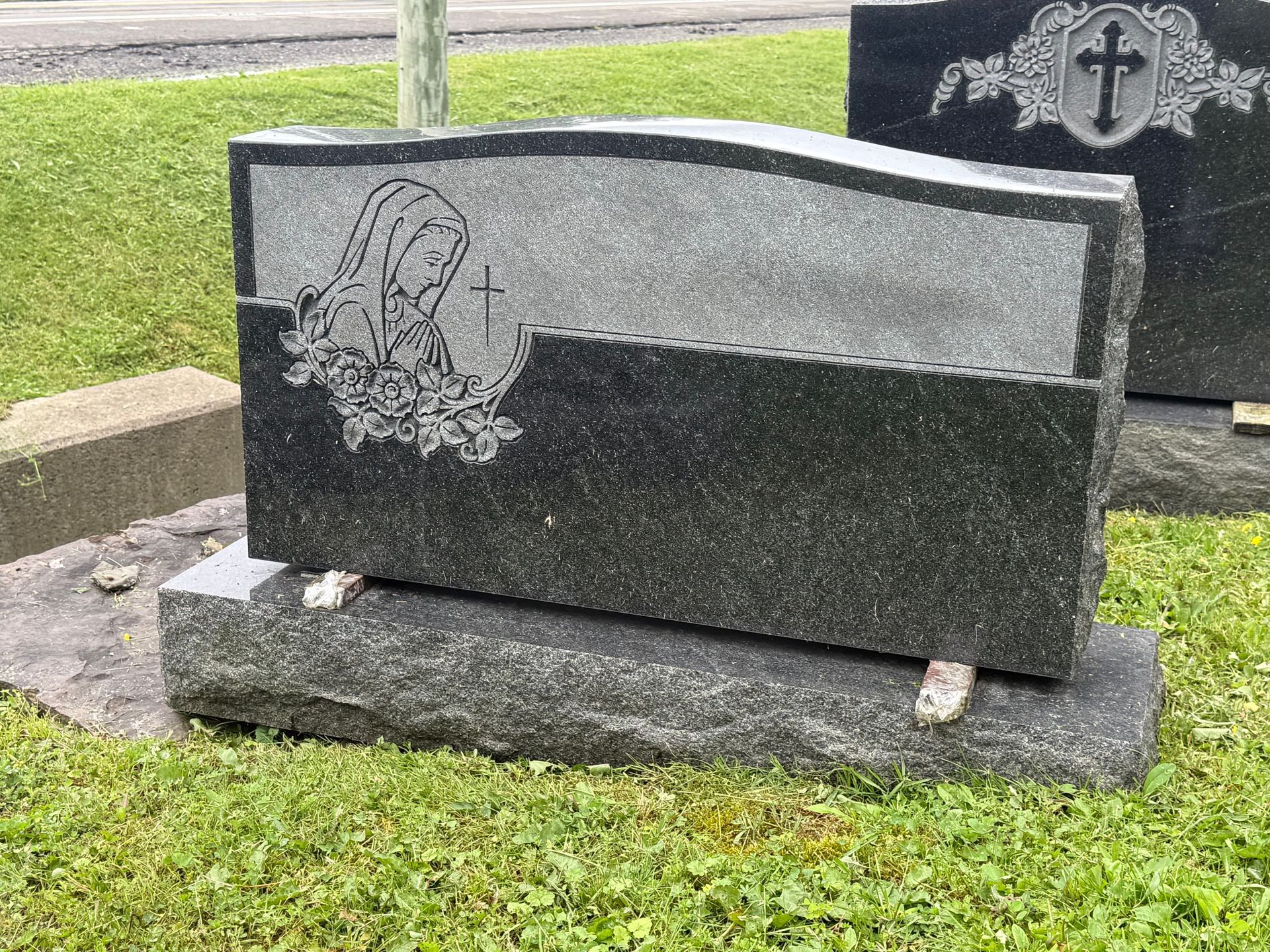 A gravestone with a cross on it is sitting in the grass.