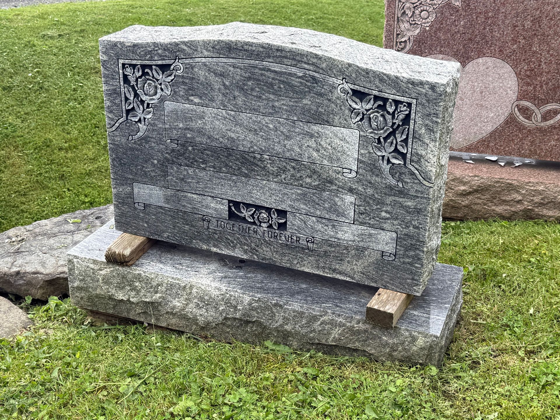 A gravestone is sitting in the grass in a cemetery.