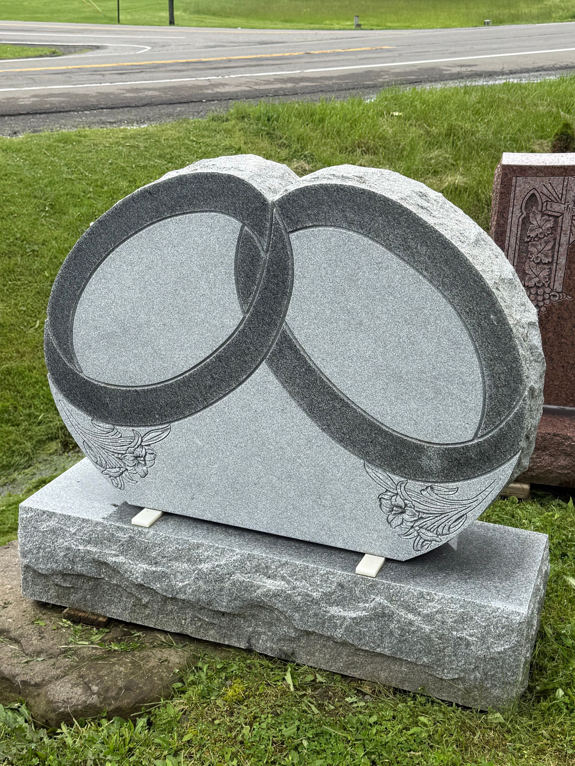 A gravestone with two circles on it is sitting in the grass.