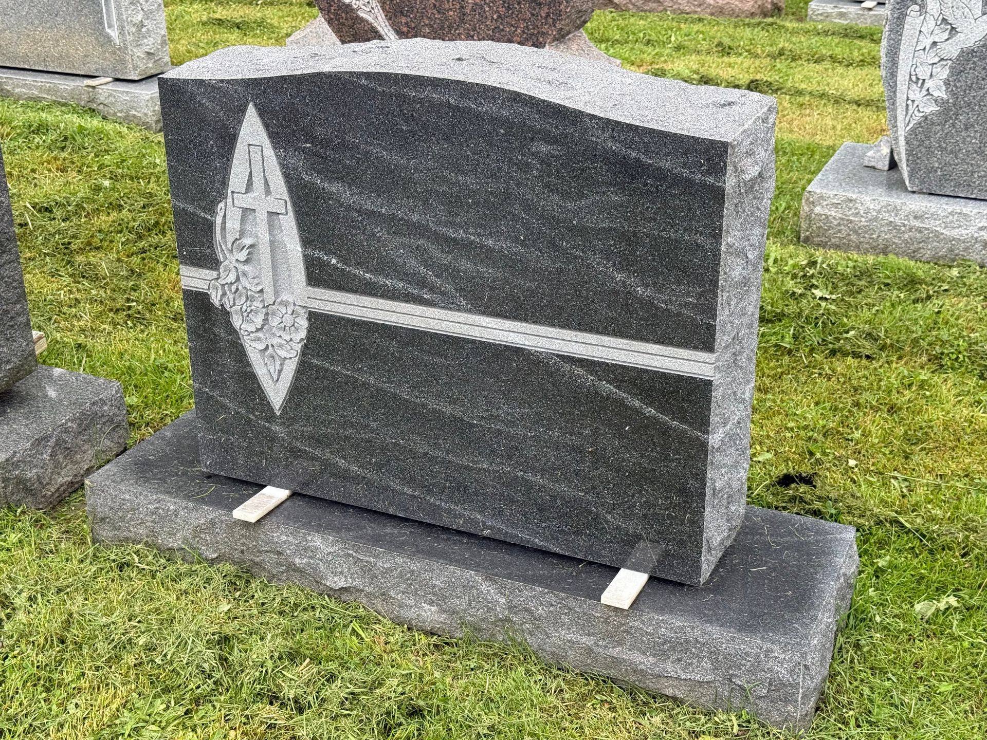 A statue of a bird is sitting on top of a grave in a cemetery.