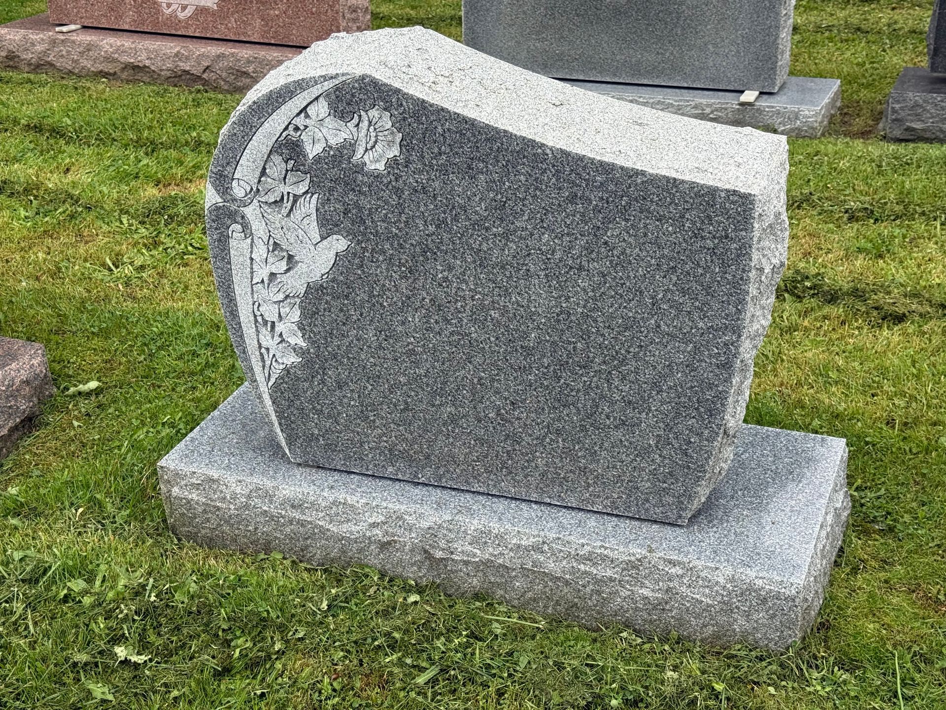 A gravestone is sitting in the grass in a cemetery.