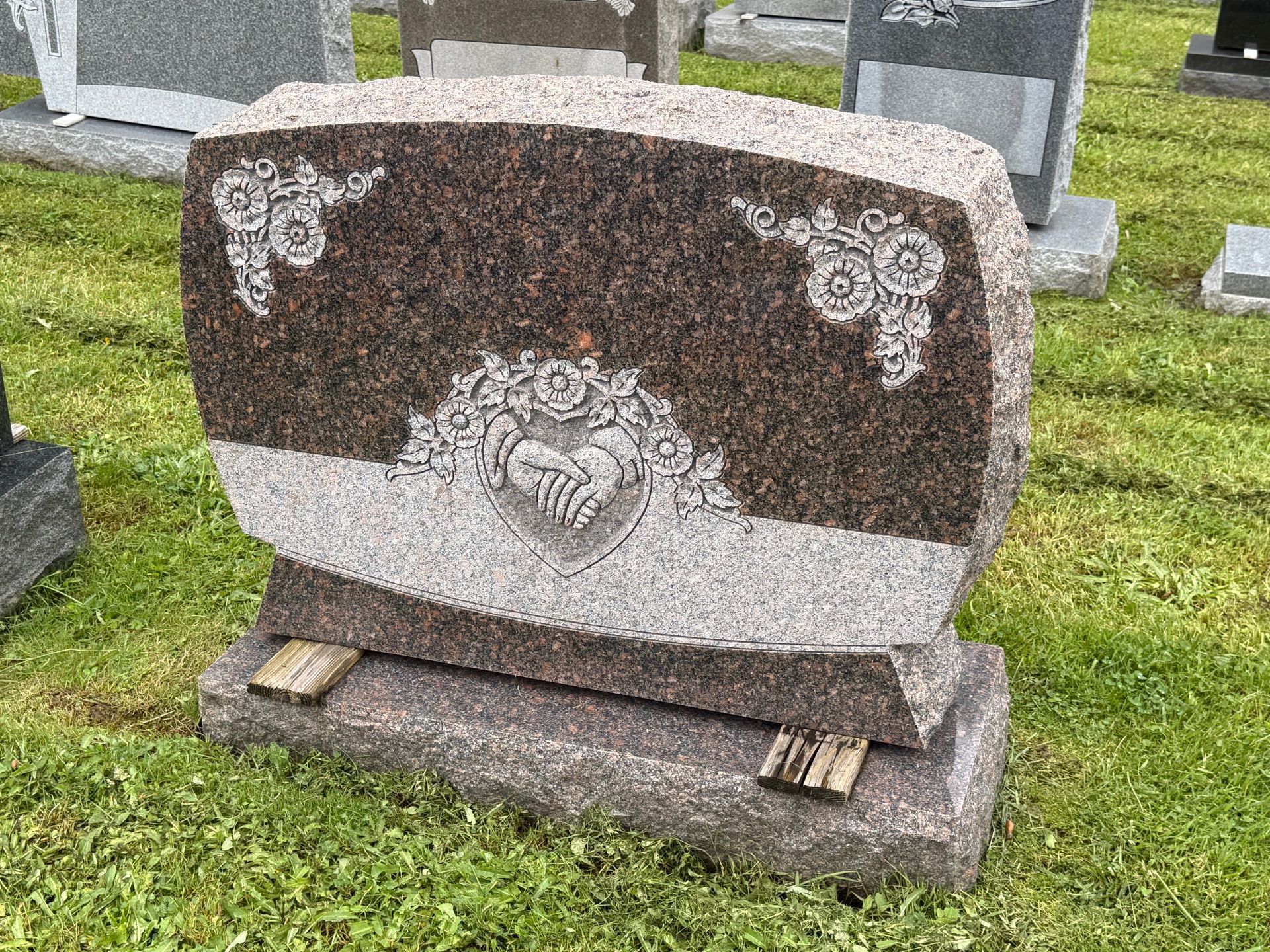 A gravestone is sitting in the grass in a cemetery.