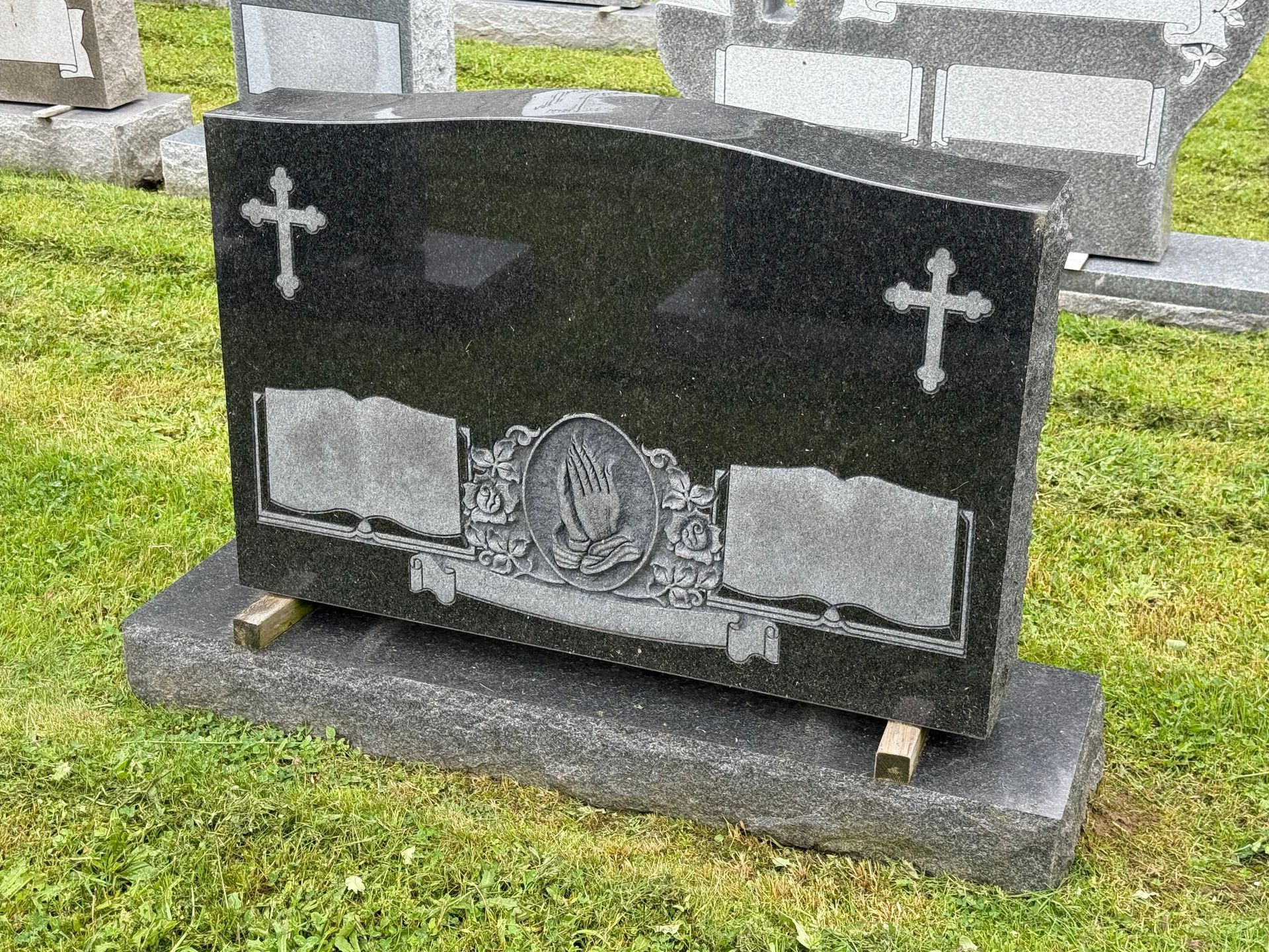 A black gravestone with two crosses on it is in a cemetery.