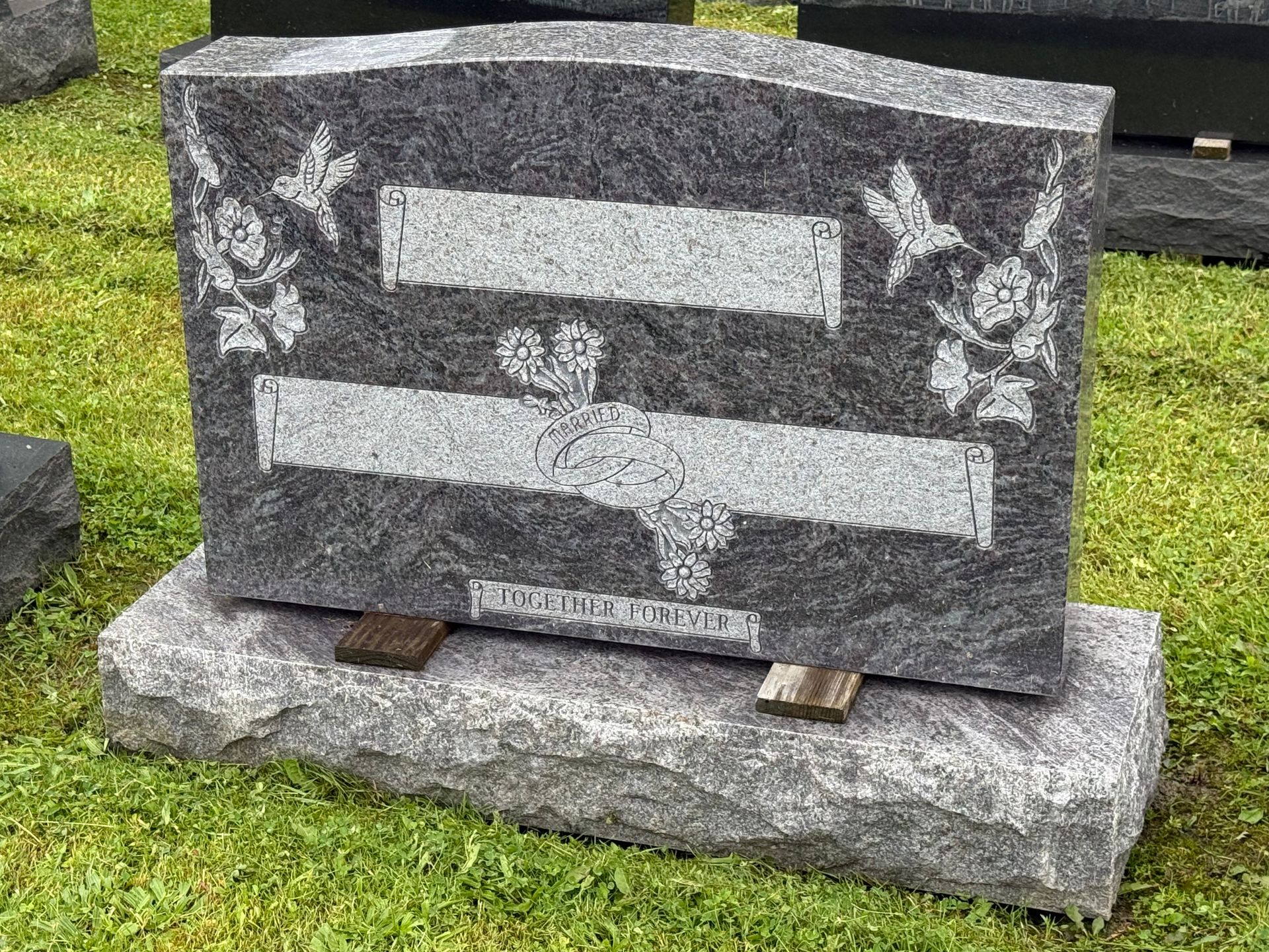 A gravestone is sitting in the grass in a cemetery.