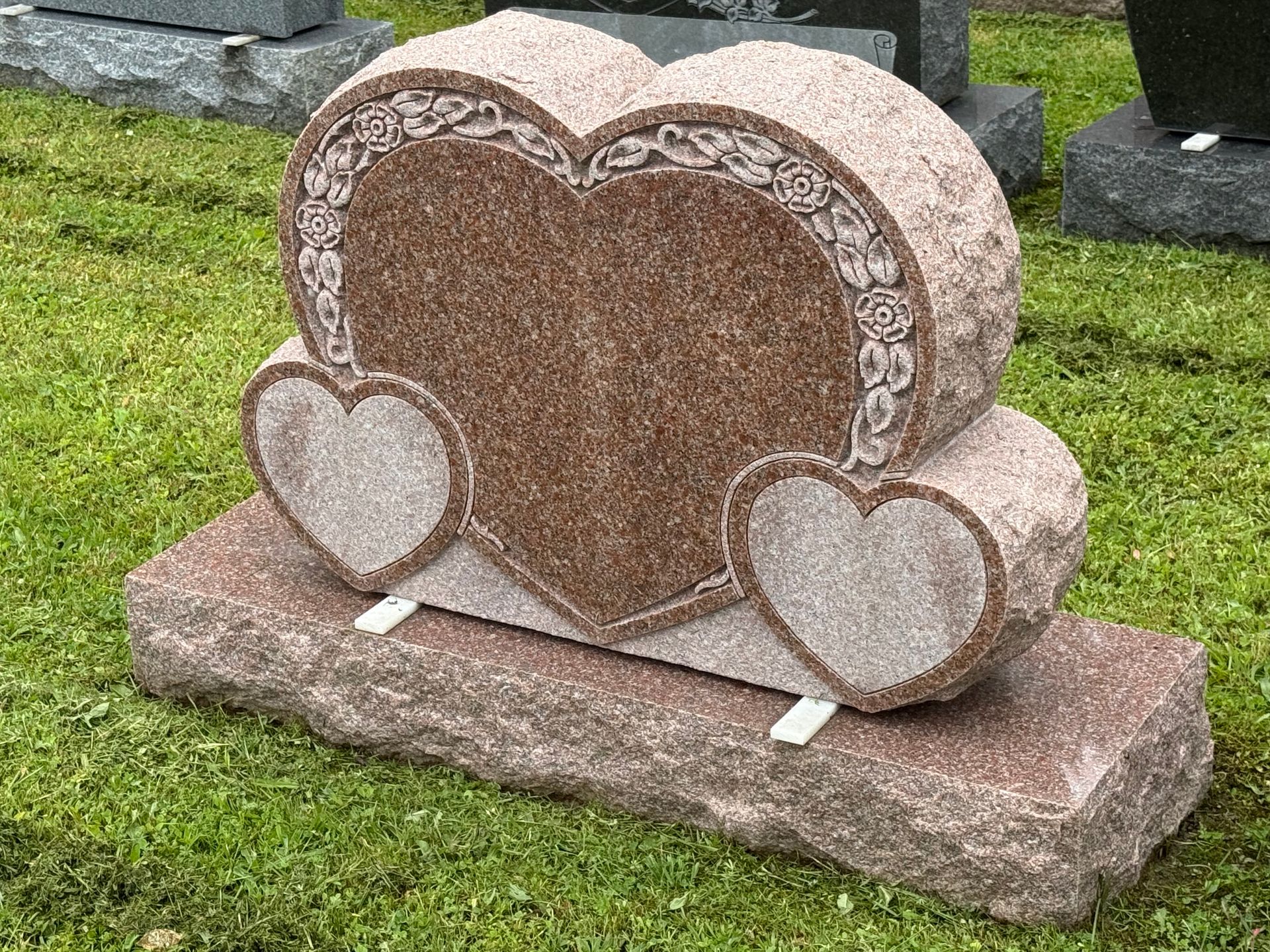 A gravestone in the shape of a heart with two hearts on it.