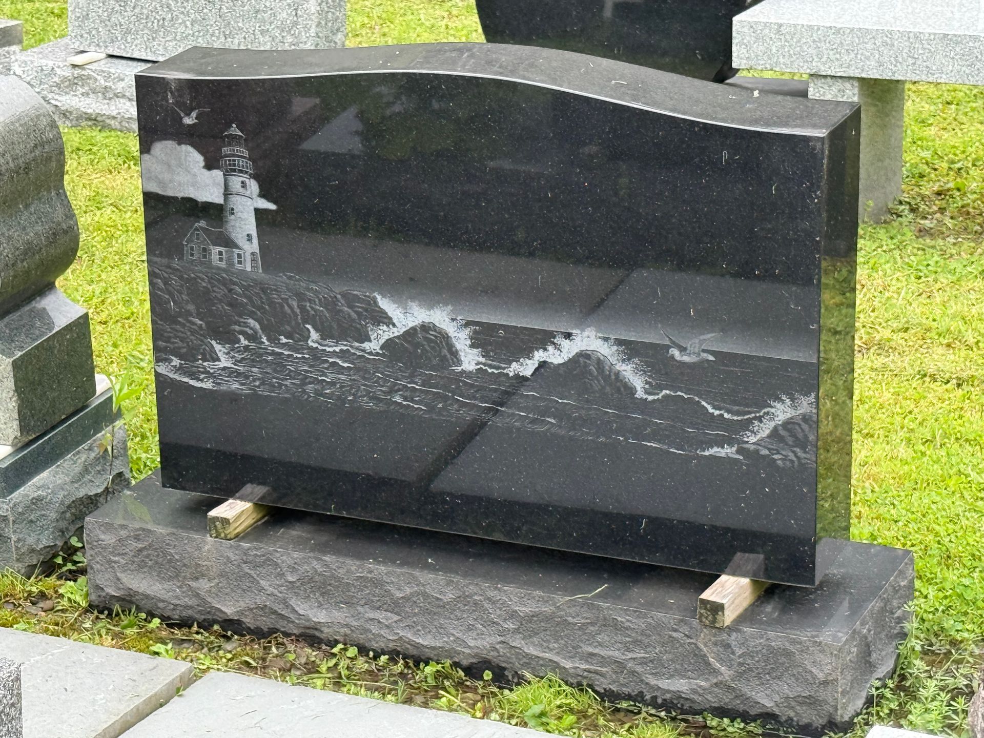 A black gravestone with a lighthouse on it