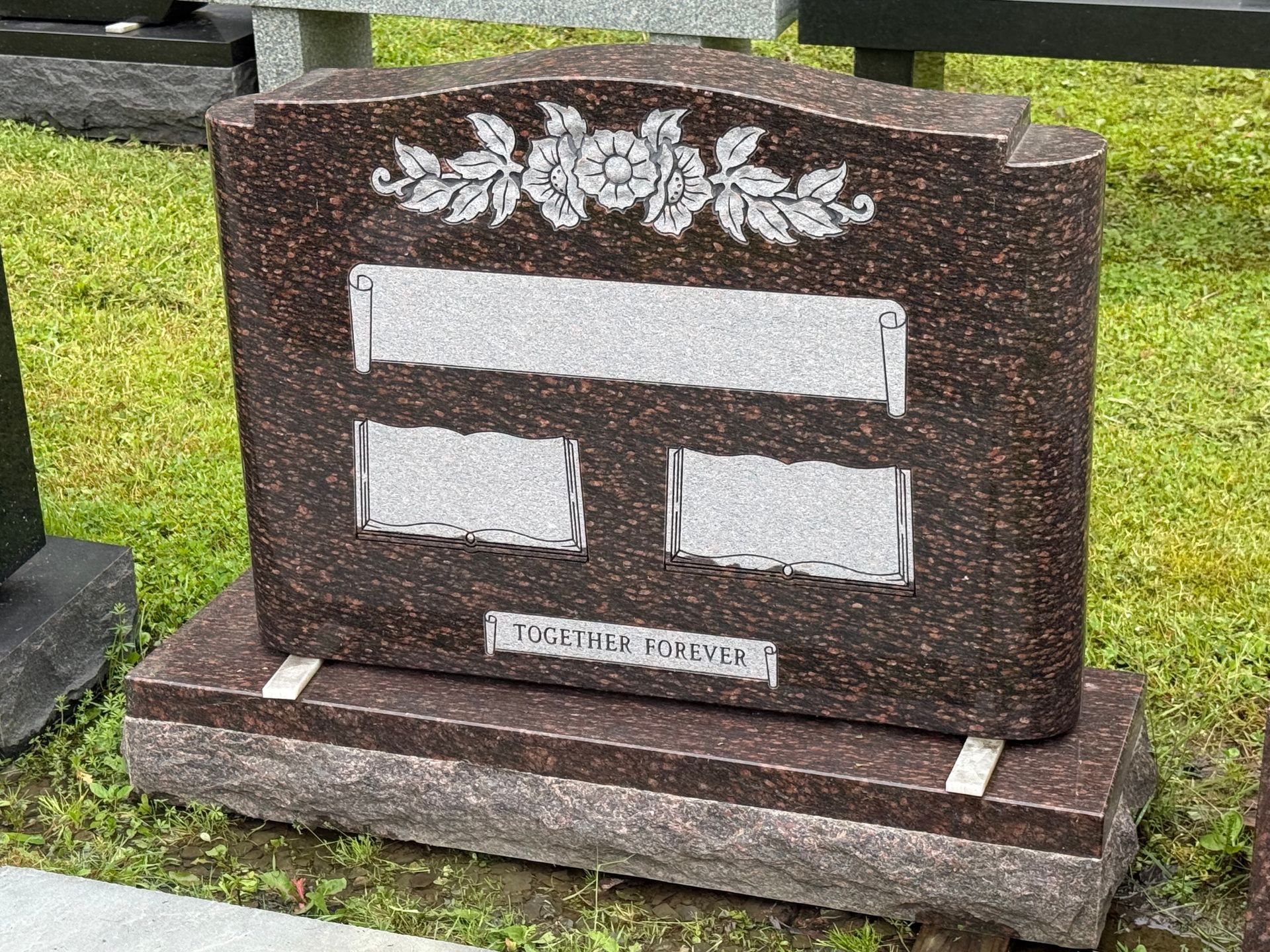 A gravestone is sitting in the grass in a cemetery.