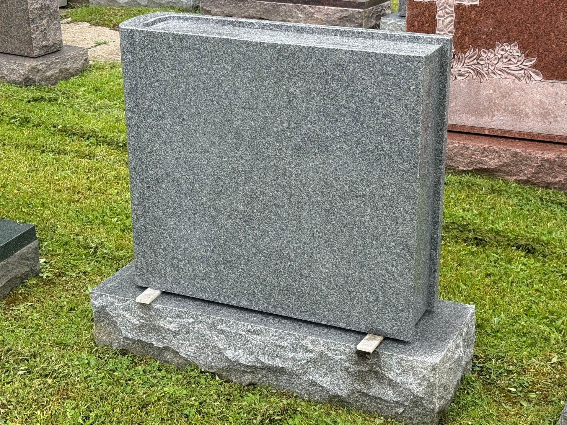 A gravestone is sitting in the grass in a cemetery.