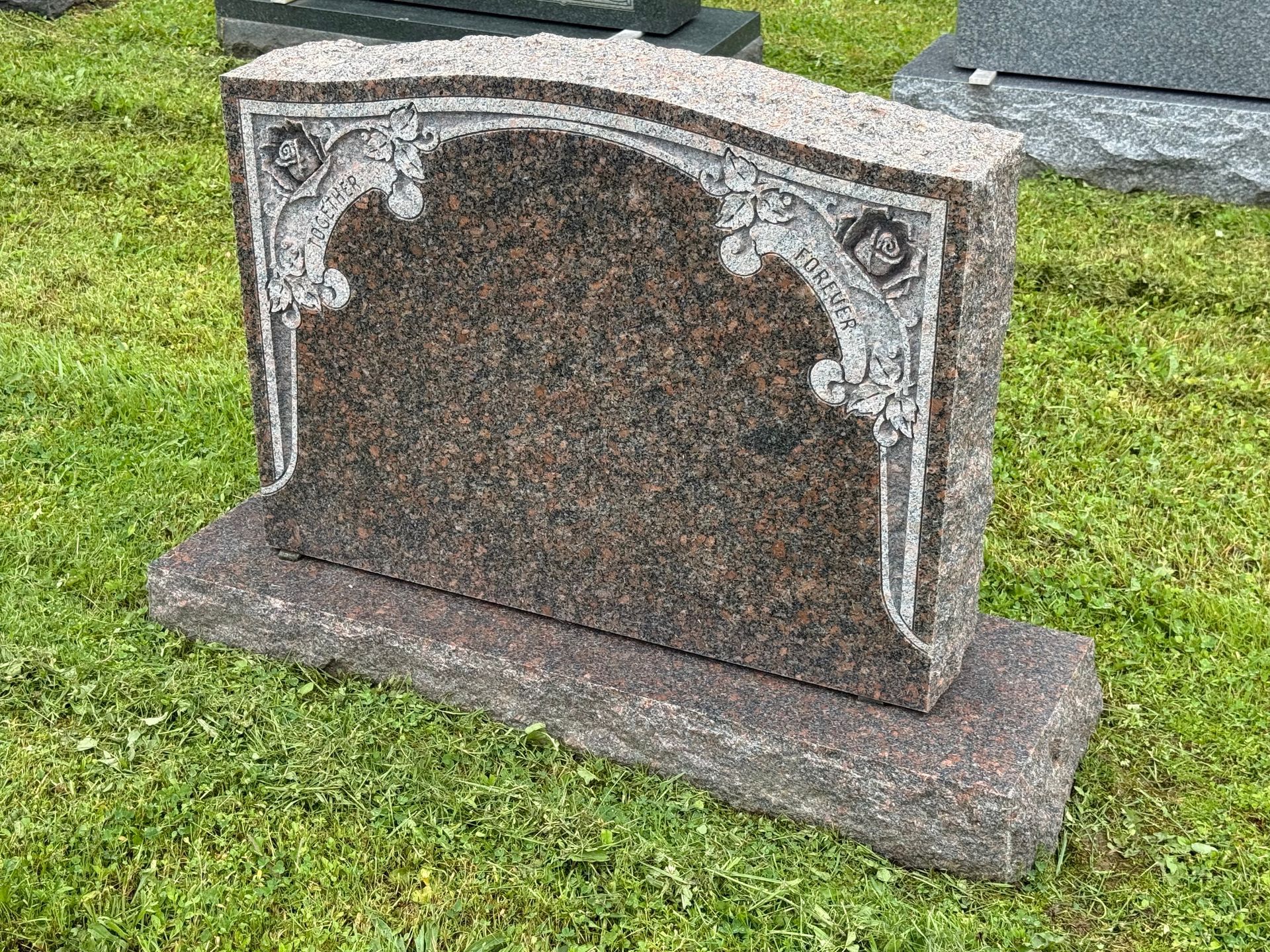 A gravestone is sitting on top of a lush green field.