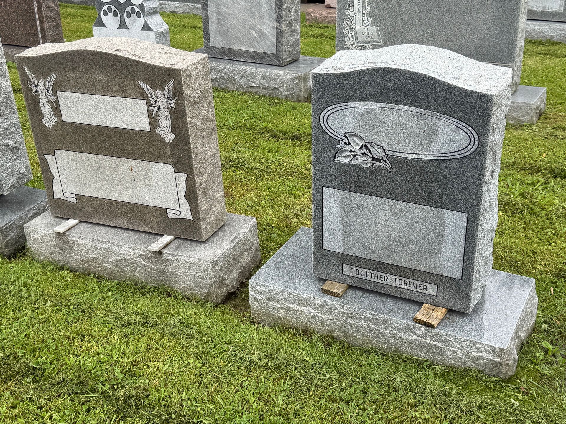 A couple of gravestones sitting on top of a lush green field.