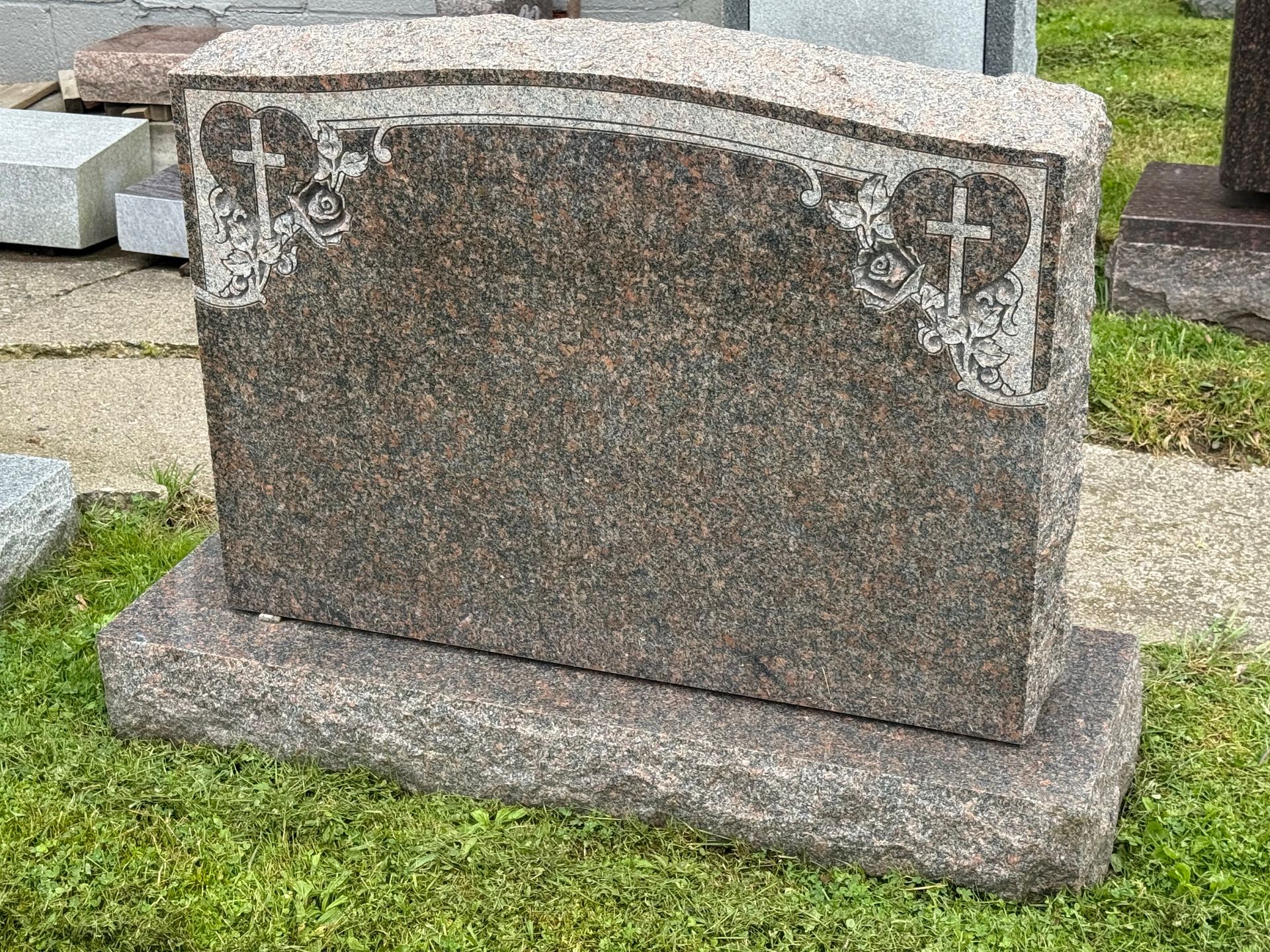 A gravestone is sitting in the grass in a cemetery.