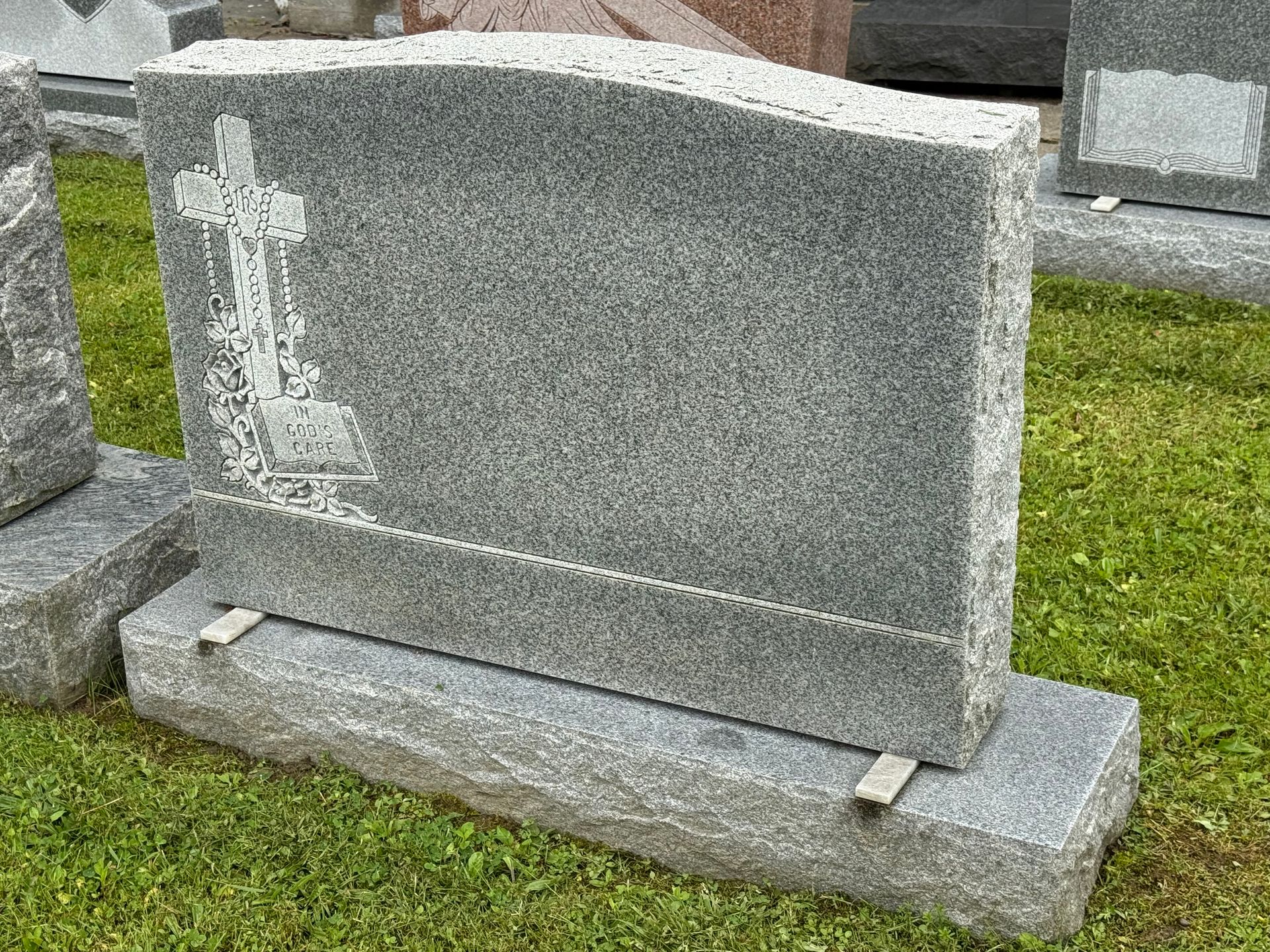 A gravestone with a cross on it is sitting in the grass.