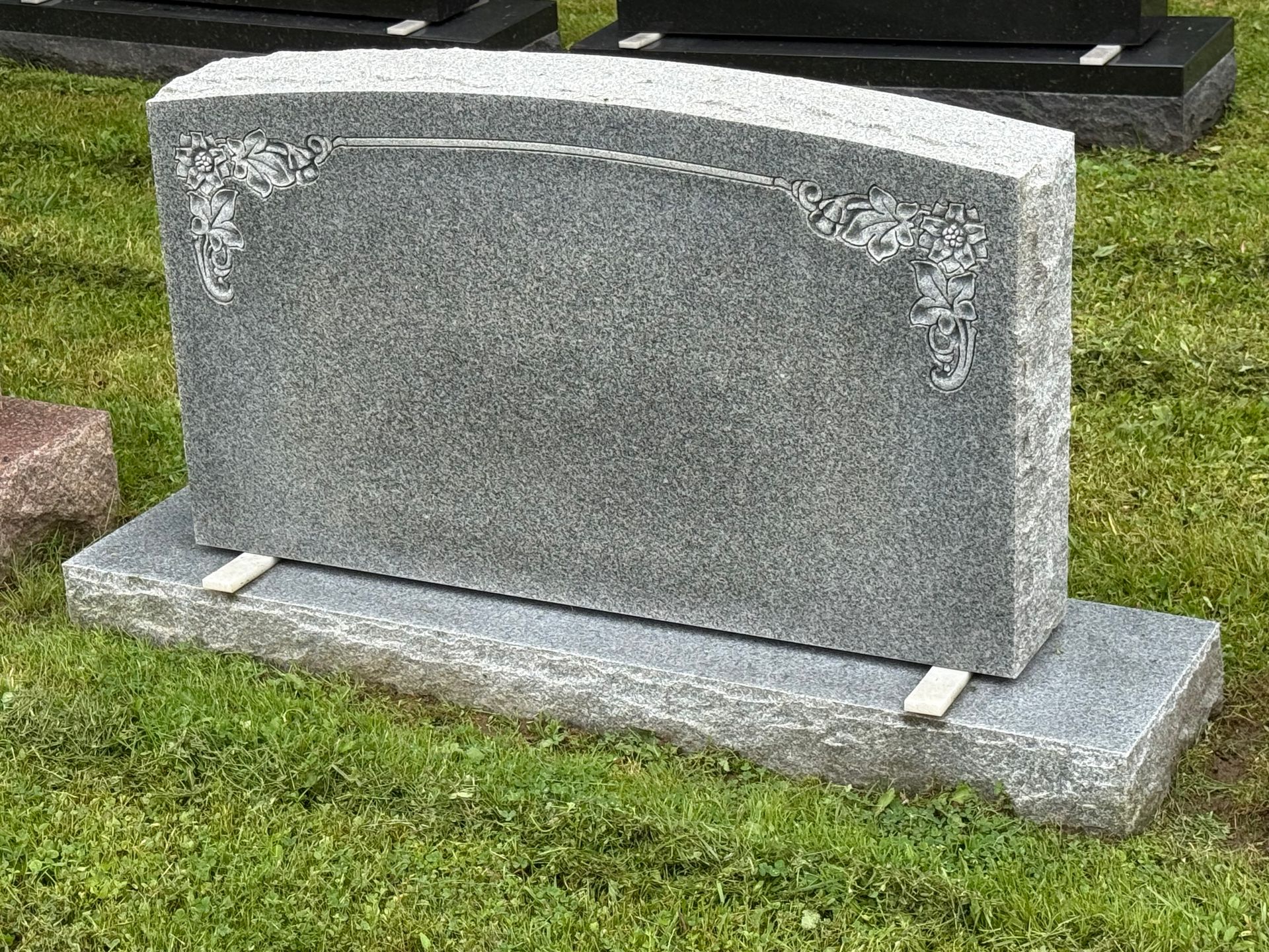 A gravestone is sitting in the grass in a cemetery.