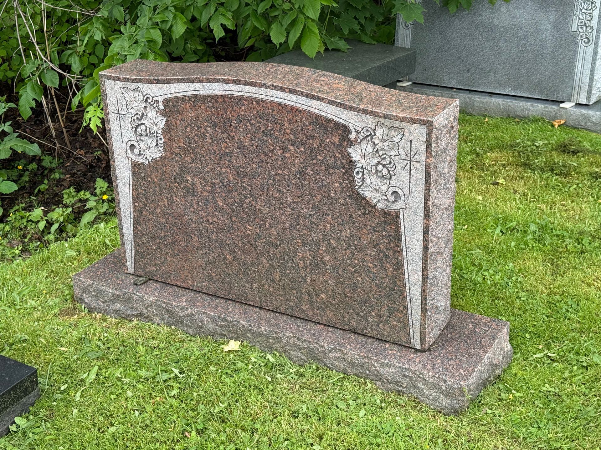 A gravestone is sitting on top of a lush green field.