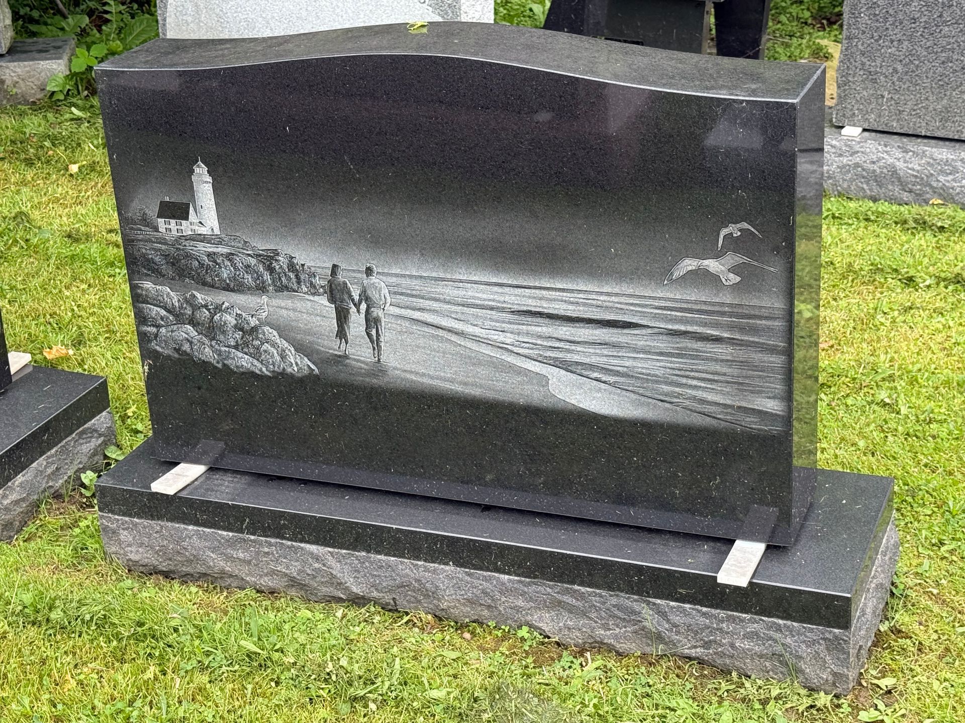 A gravestone with a picture of a lighthouse on the beach