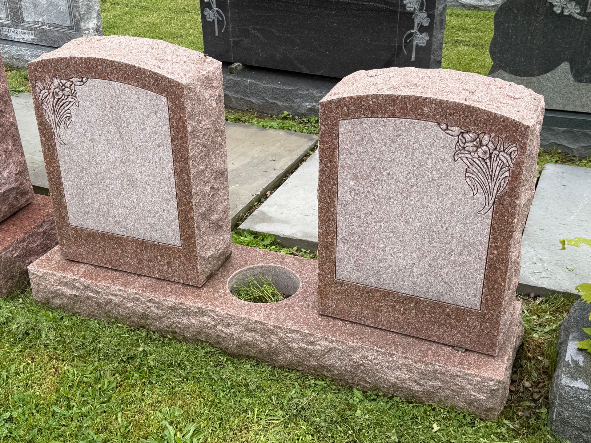 A couple of gravestones sitting on top of a lush green field.