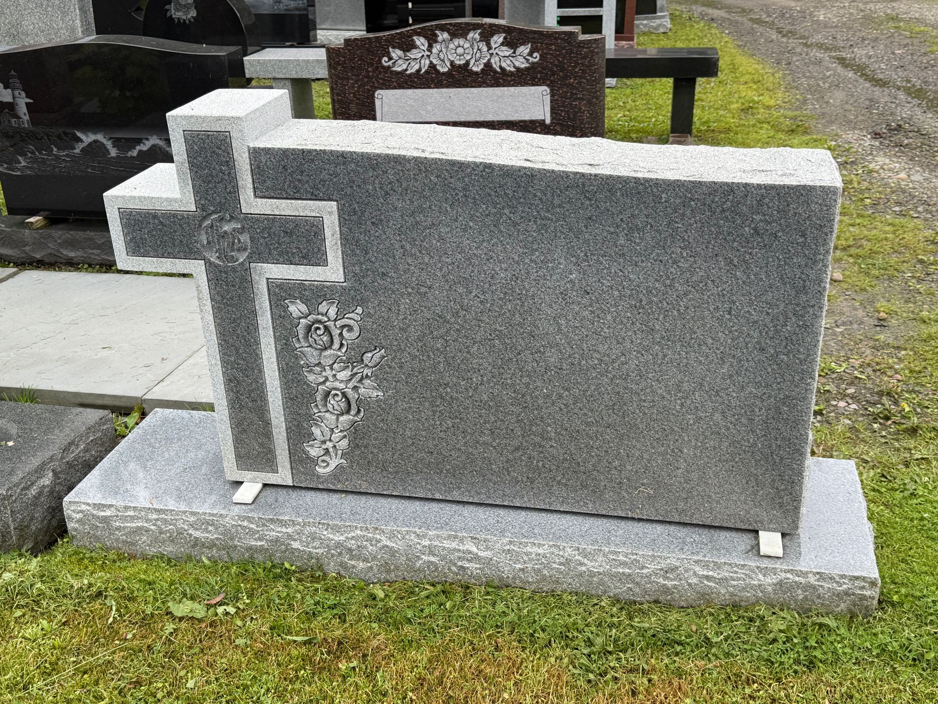 A gravestone with a cross on it is sitting in the grass.