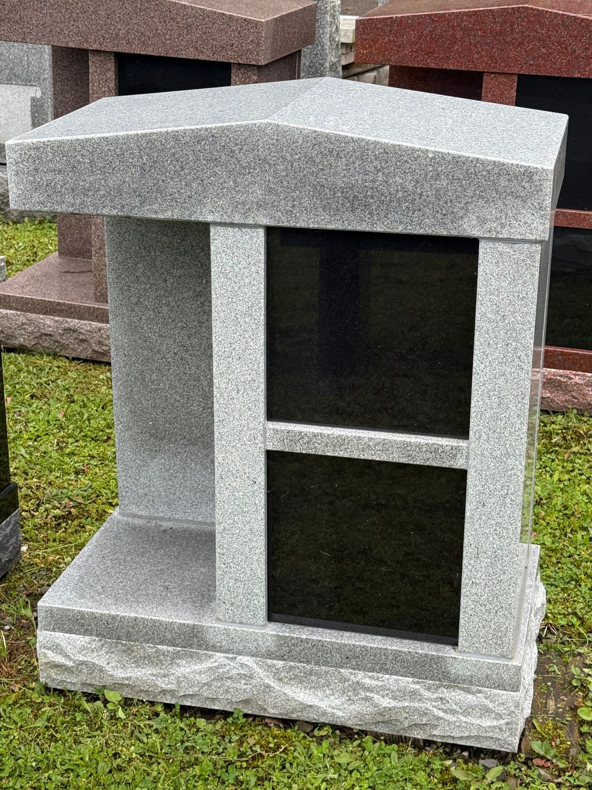 A gray and black stone monument is sitting on top of a lush green field.