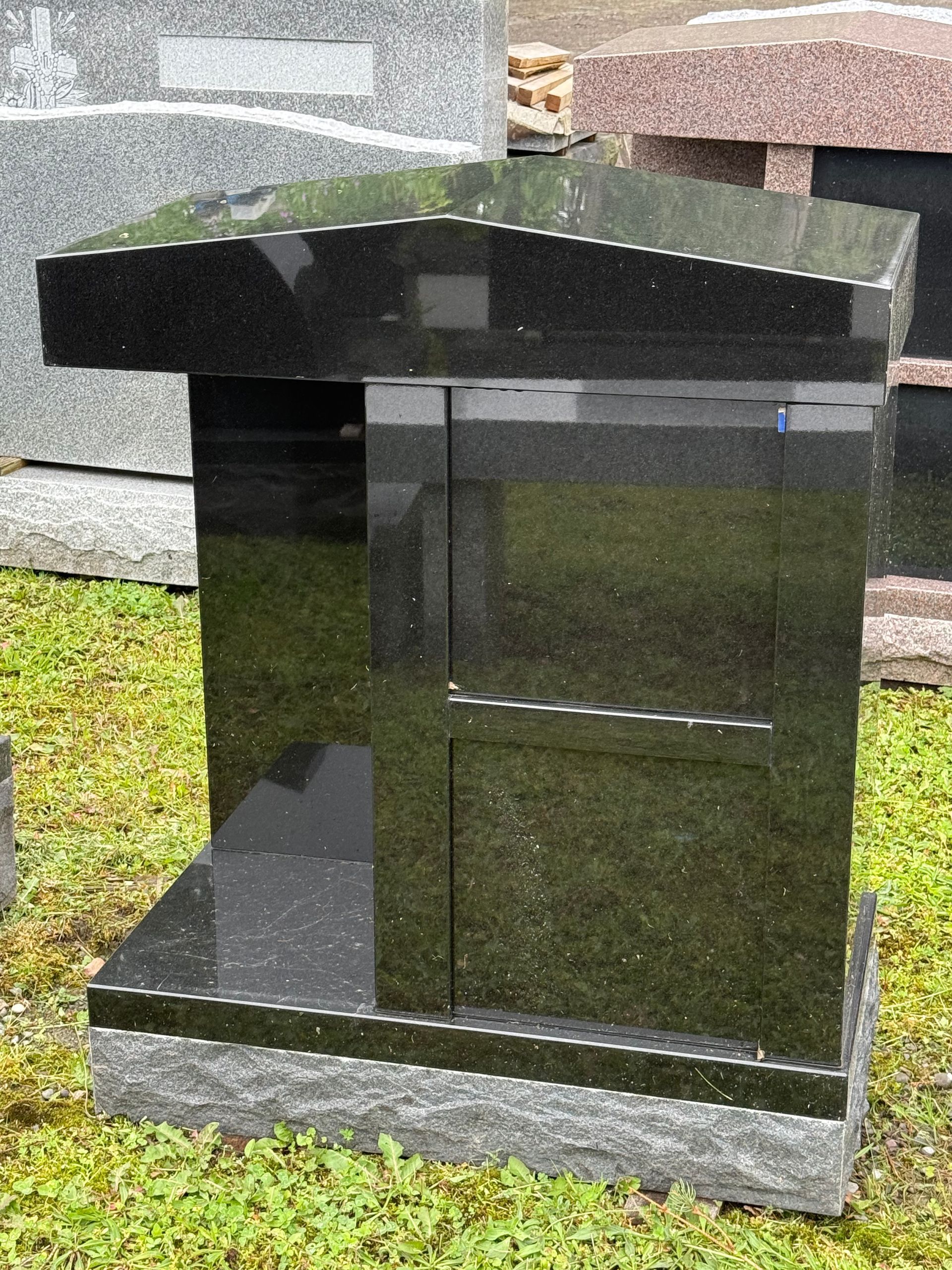 A black granite tombstone is sitting in the grass