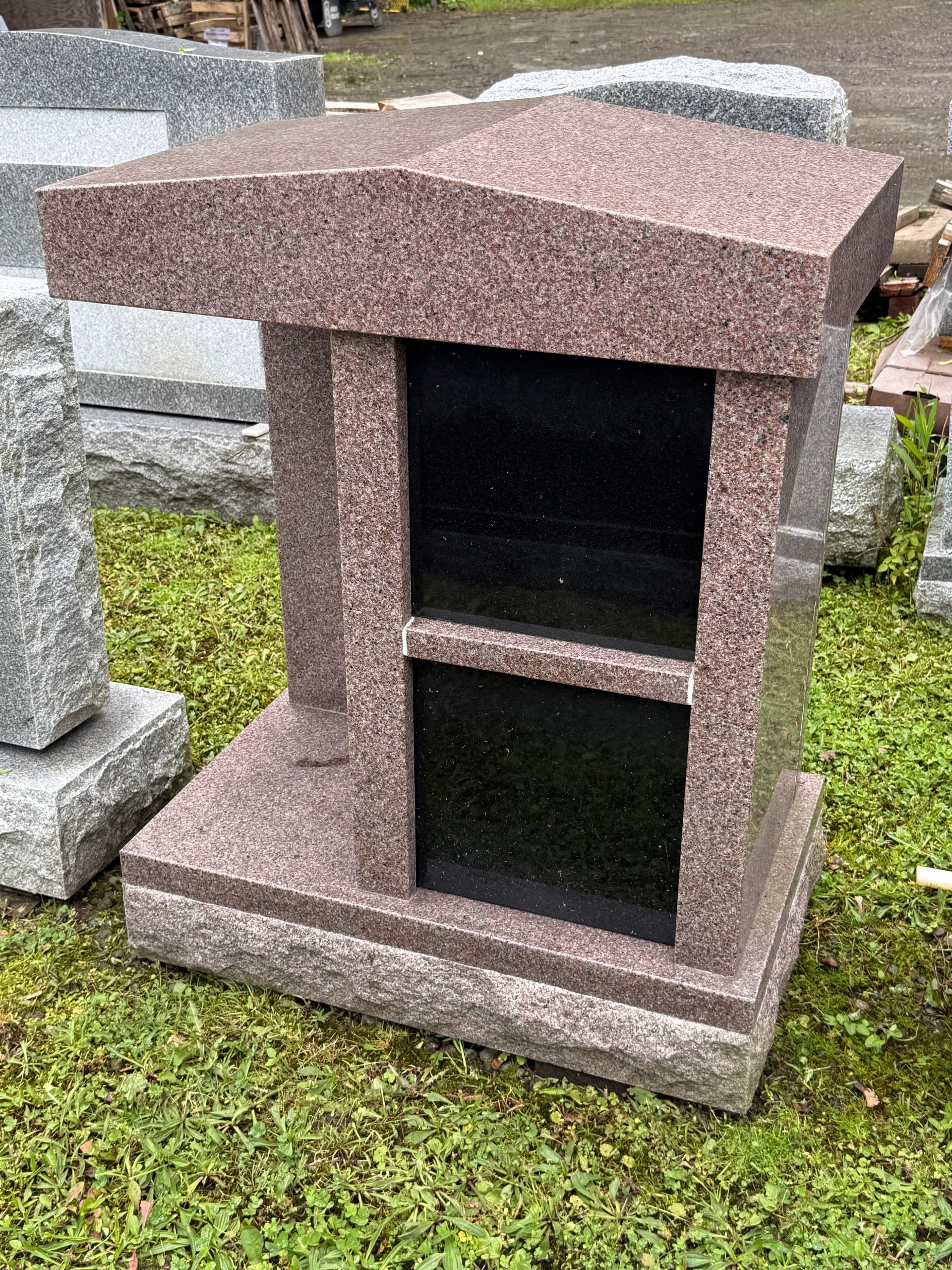 A small granite memorial sitting on top of a lush green field.