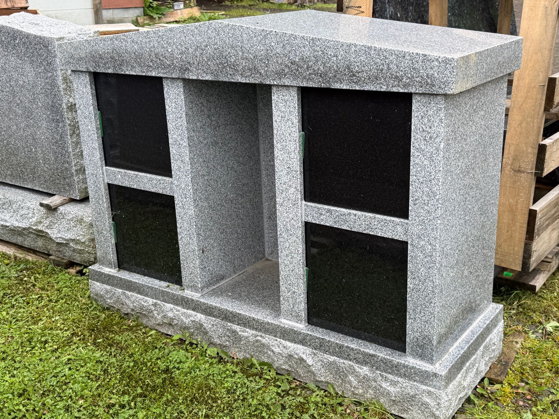 A gray and black granite monument is sitting on top of a lush green field.