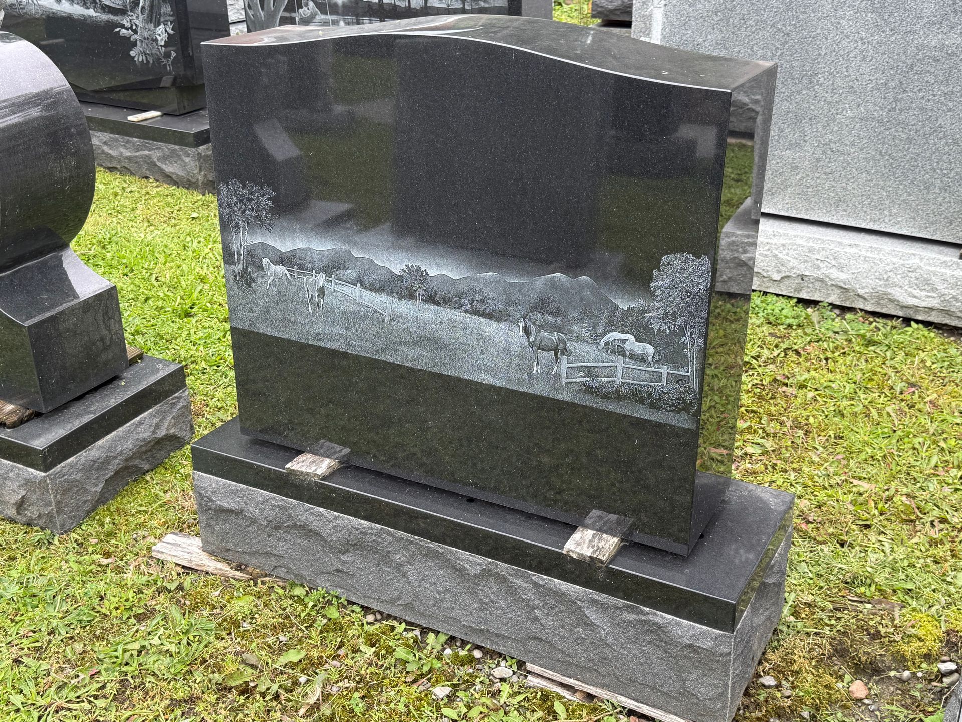 A black gravestone with a picture of a field on it