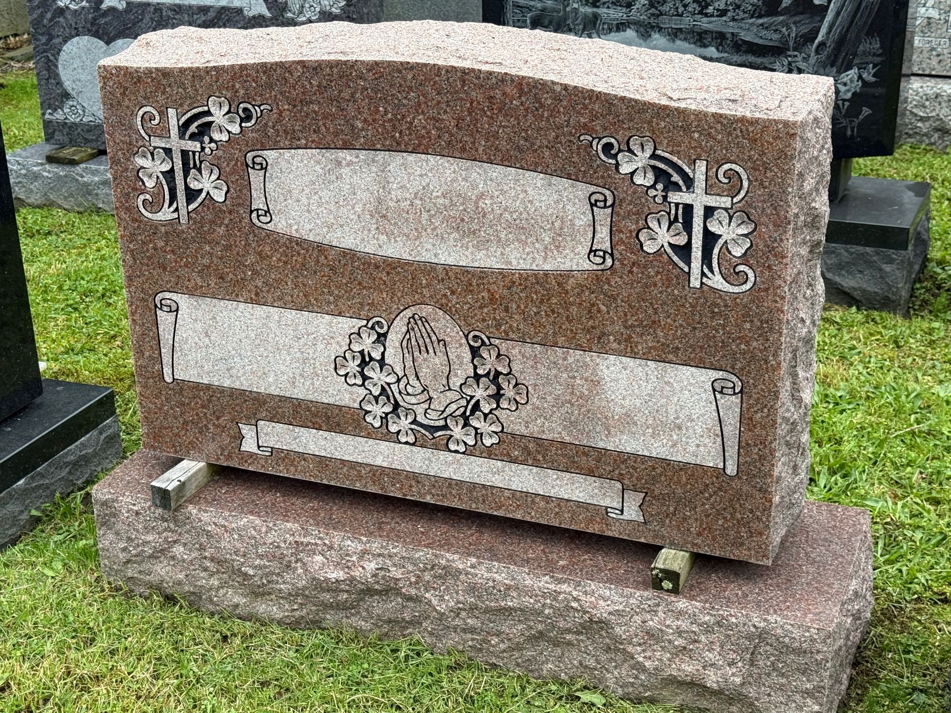 A gravestone is sitting in the grass in a cemetery.