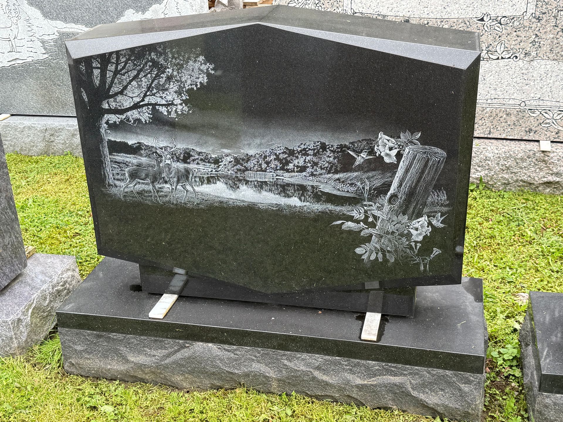 A black gravestone with a picture of a tree on it