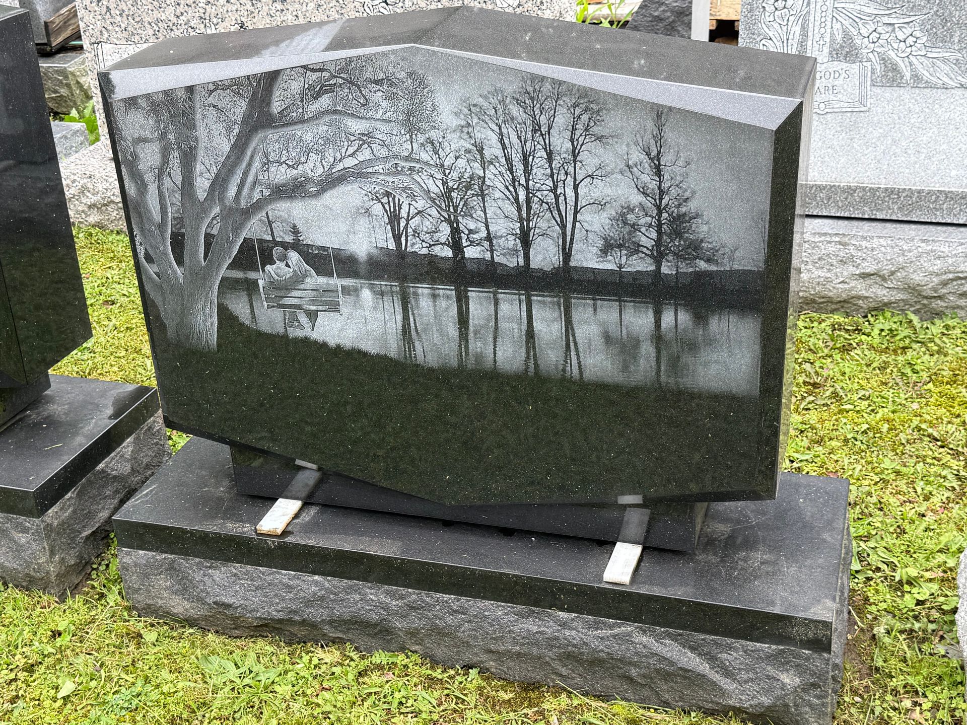 A gravestone with a picture of a lake and trees on it